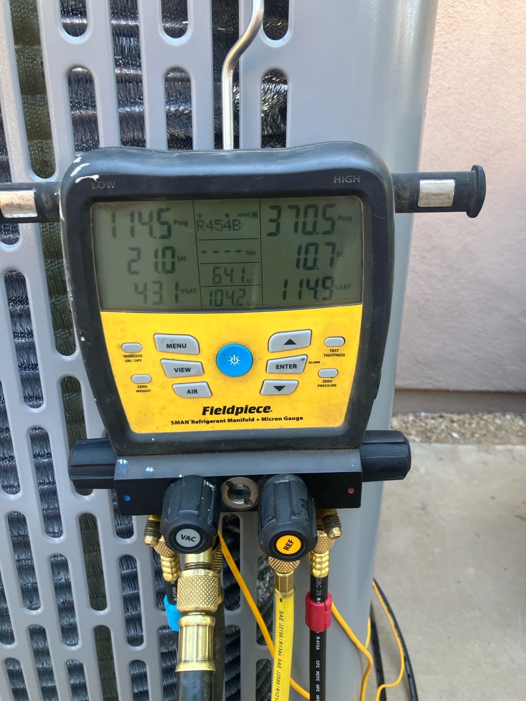 Digital manifold on the outdoor unit shows operating pressures and temperatures during system commissioning with R-454B refrigerant.