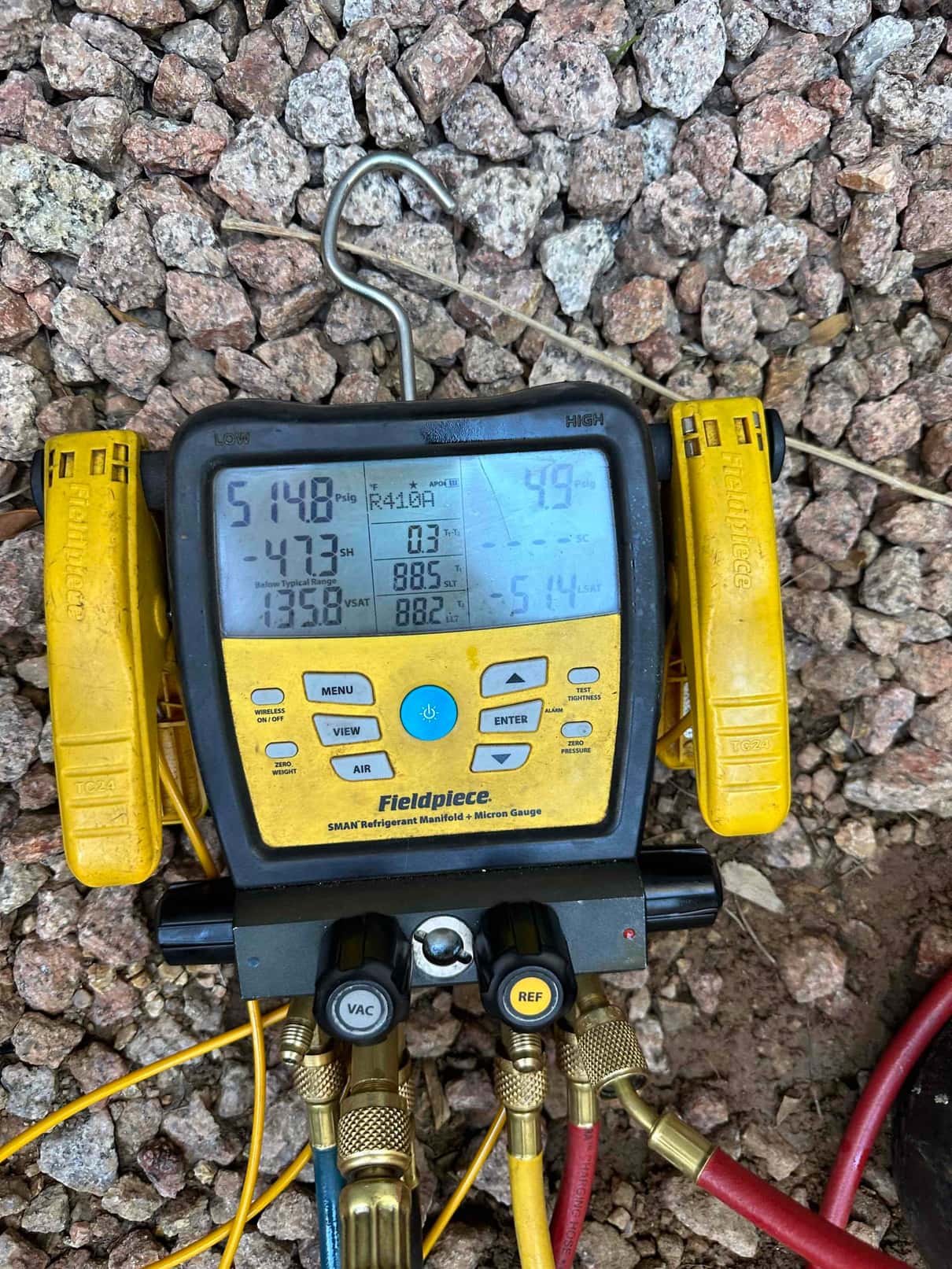 Digital manifold shows operating pressures while commissioning a mini‑split system, with hoses connected to the service ports during testing.