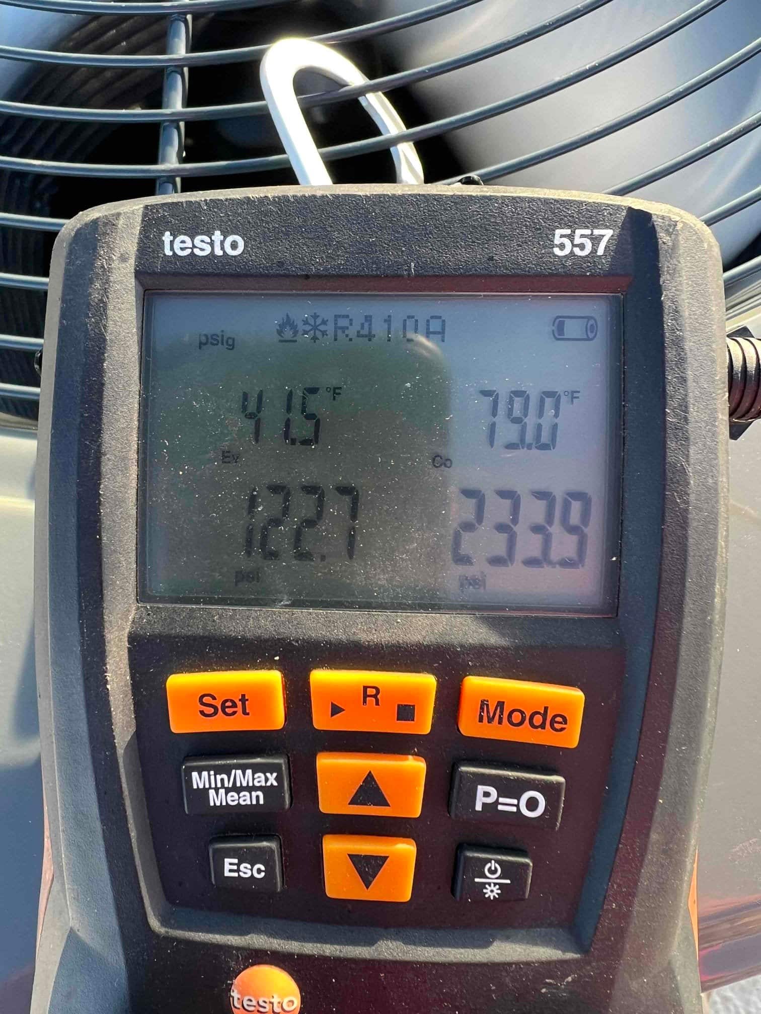 Digital manifold shows operating pressures on an outdoor condenser with R-410A selected, documenting suction and liquid pressures during commissioning.