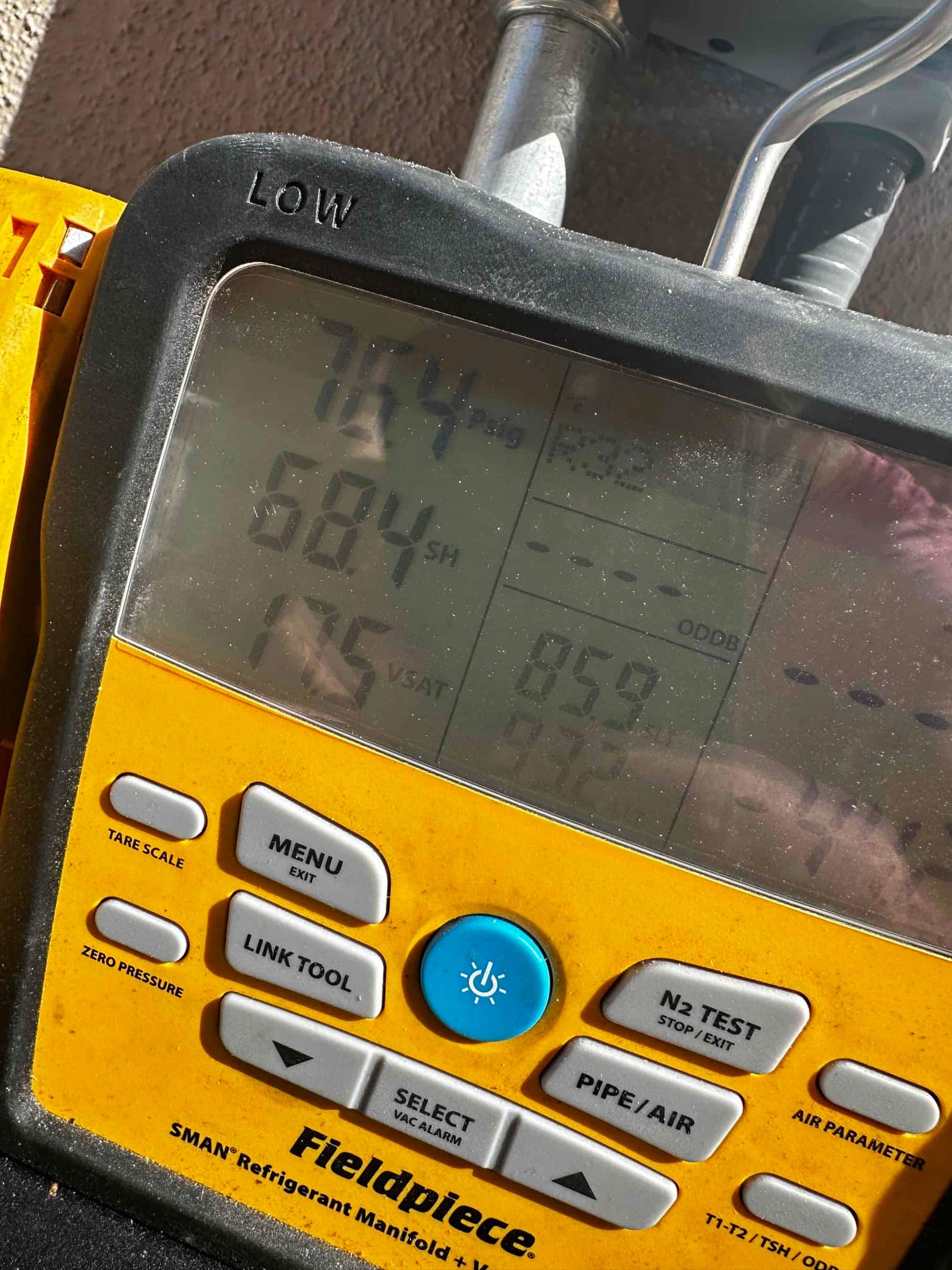 Digital manifold shows system operating with a low-side pressure reading and superheat displayed during commissioning checks.