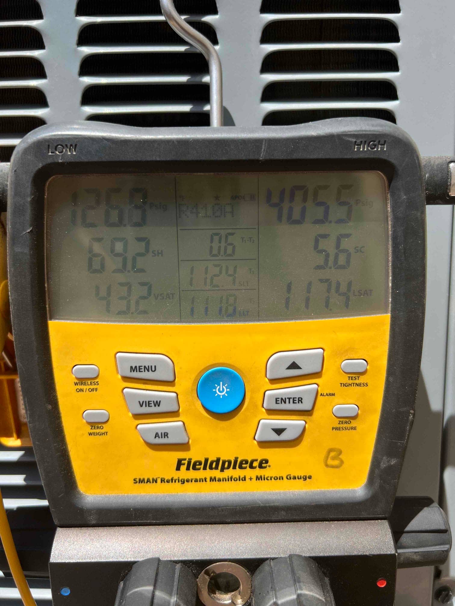 Digital manifold shows system operating pressures with low side at 126.8 PSI and high side at 405.5 PSI during commissioning.