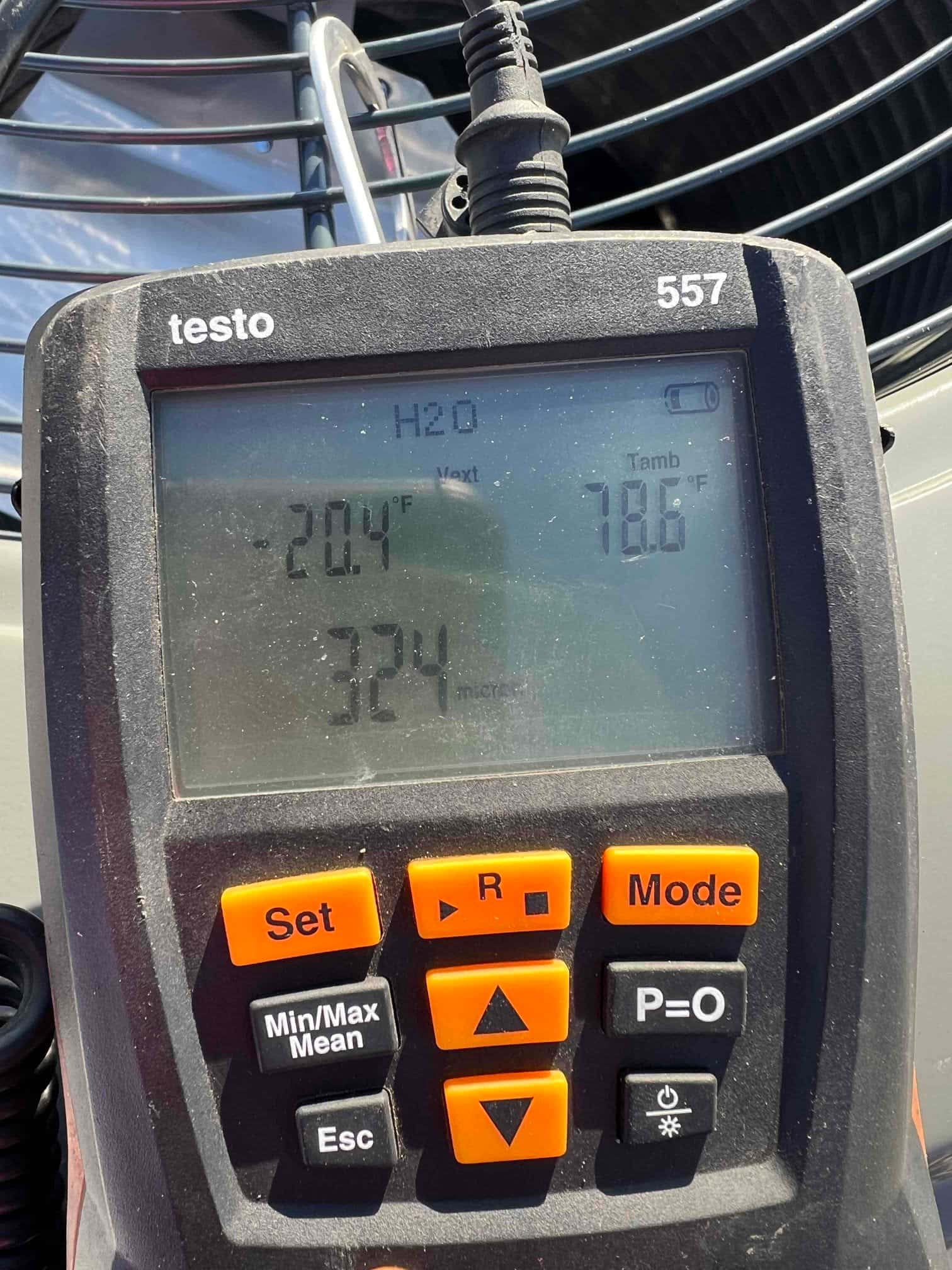 Digital micron gauge shows 324 microns during system evacuation in front of the outdoor condensing unit.