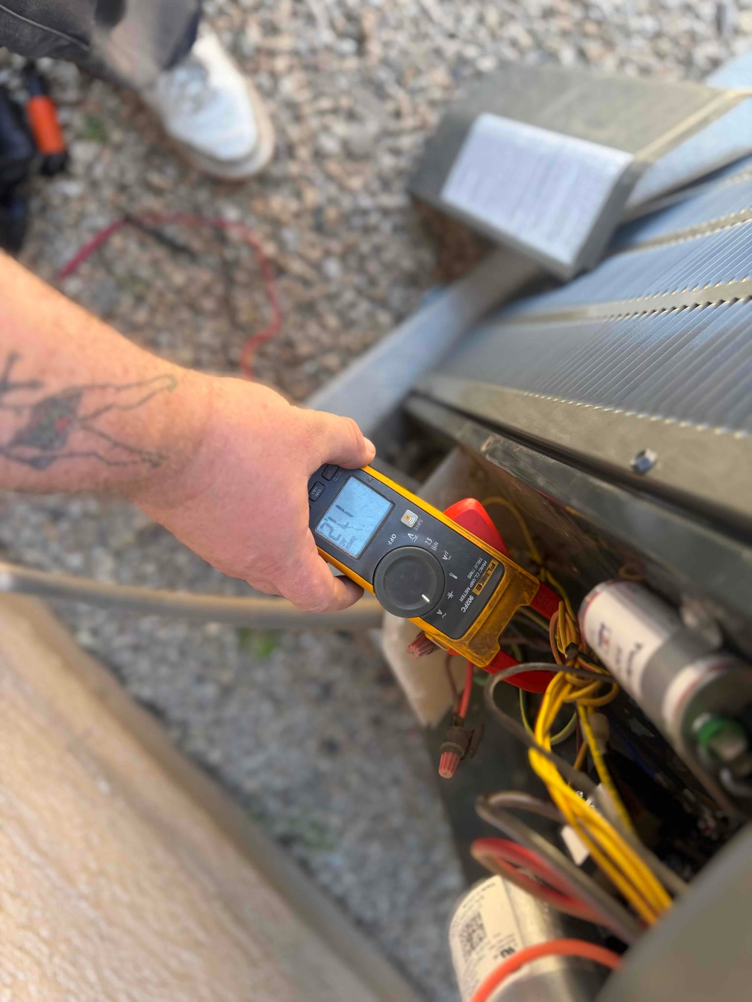 Digital multimeter measures 26.7 V on the low-voltage control wiring at the outdoor condenser unit.