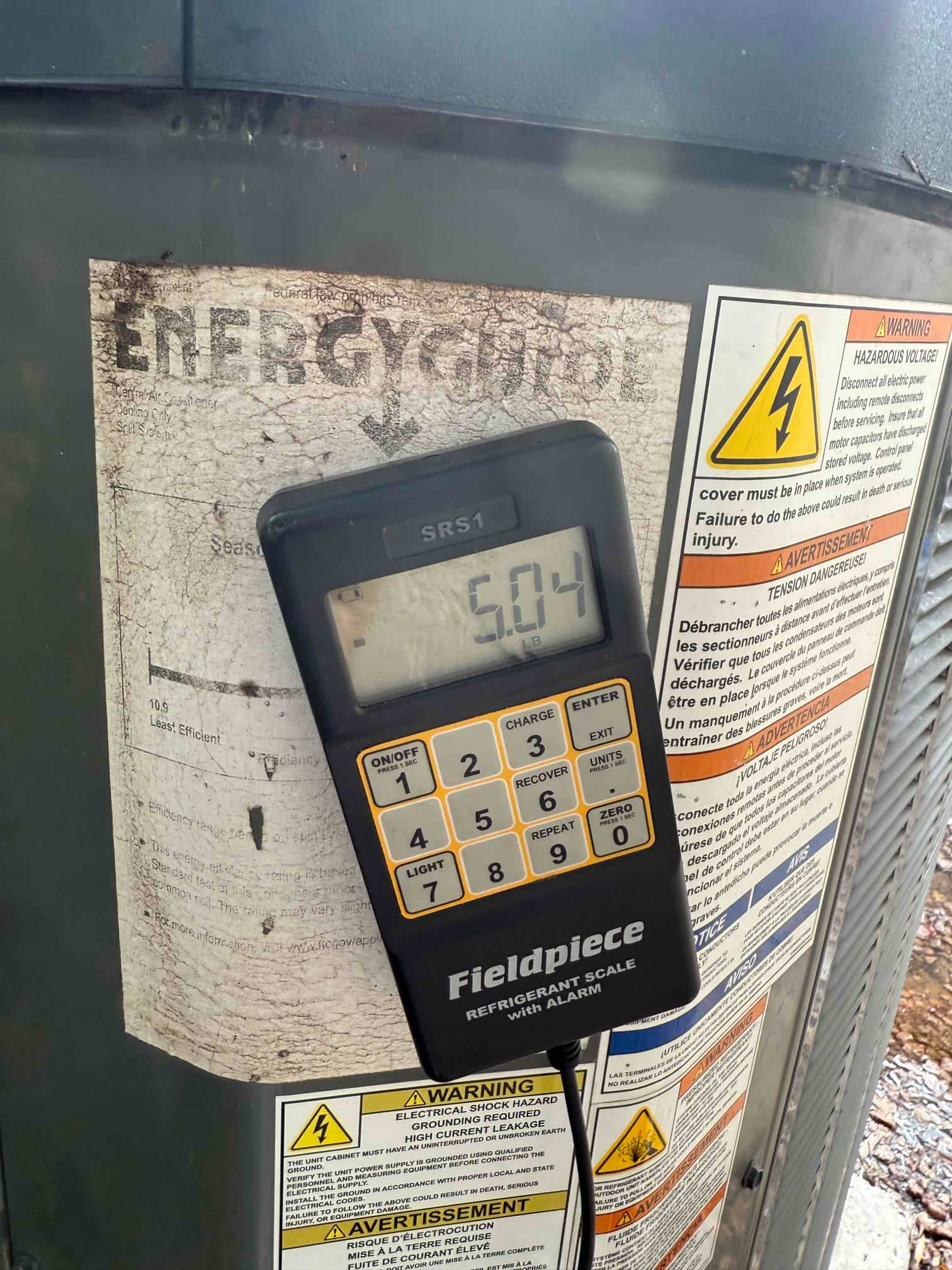 Digital refrigerant scale displays 5.04 lb while measuring added R-410A during the air conditioning recharge.