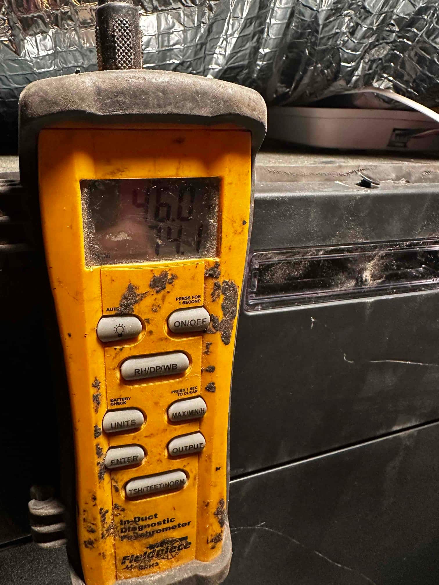 Digital thermometer at the air handler displays 46.0 degrees, documenting cold supply air temperature during commissioning.