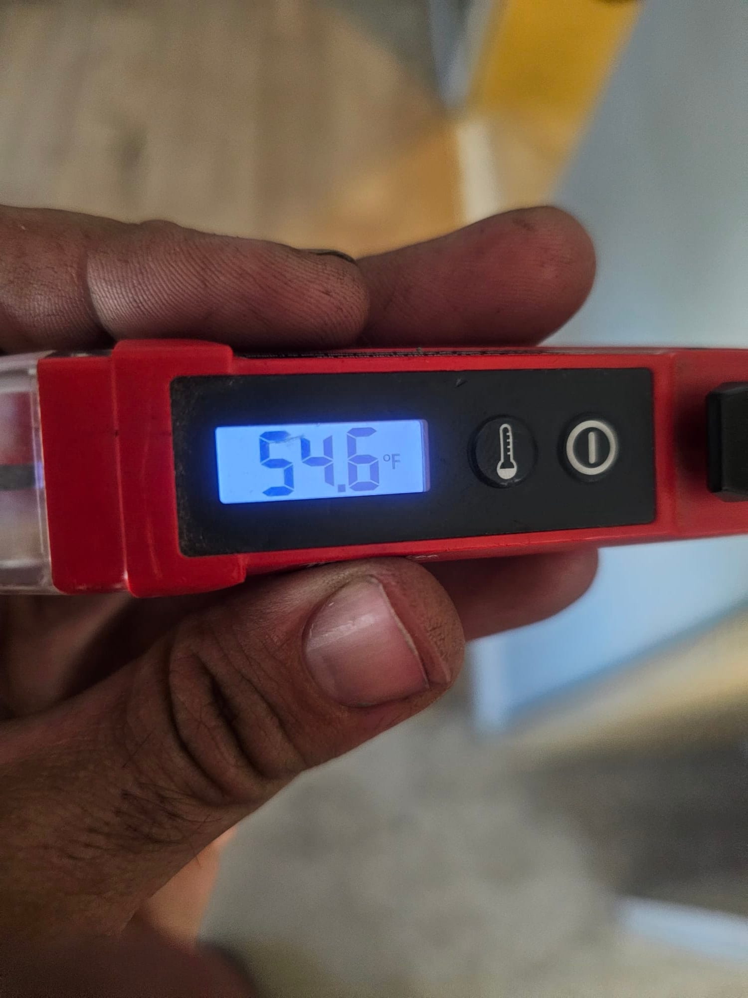 Digital thermometer displays 54.6°F, documenting cool supply air temperature during system airflow verification.