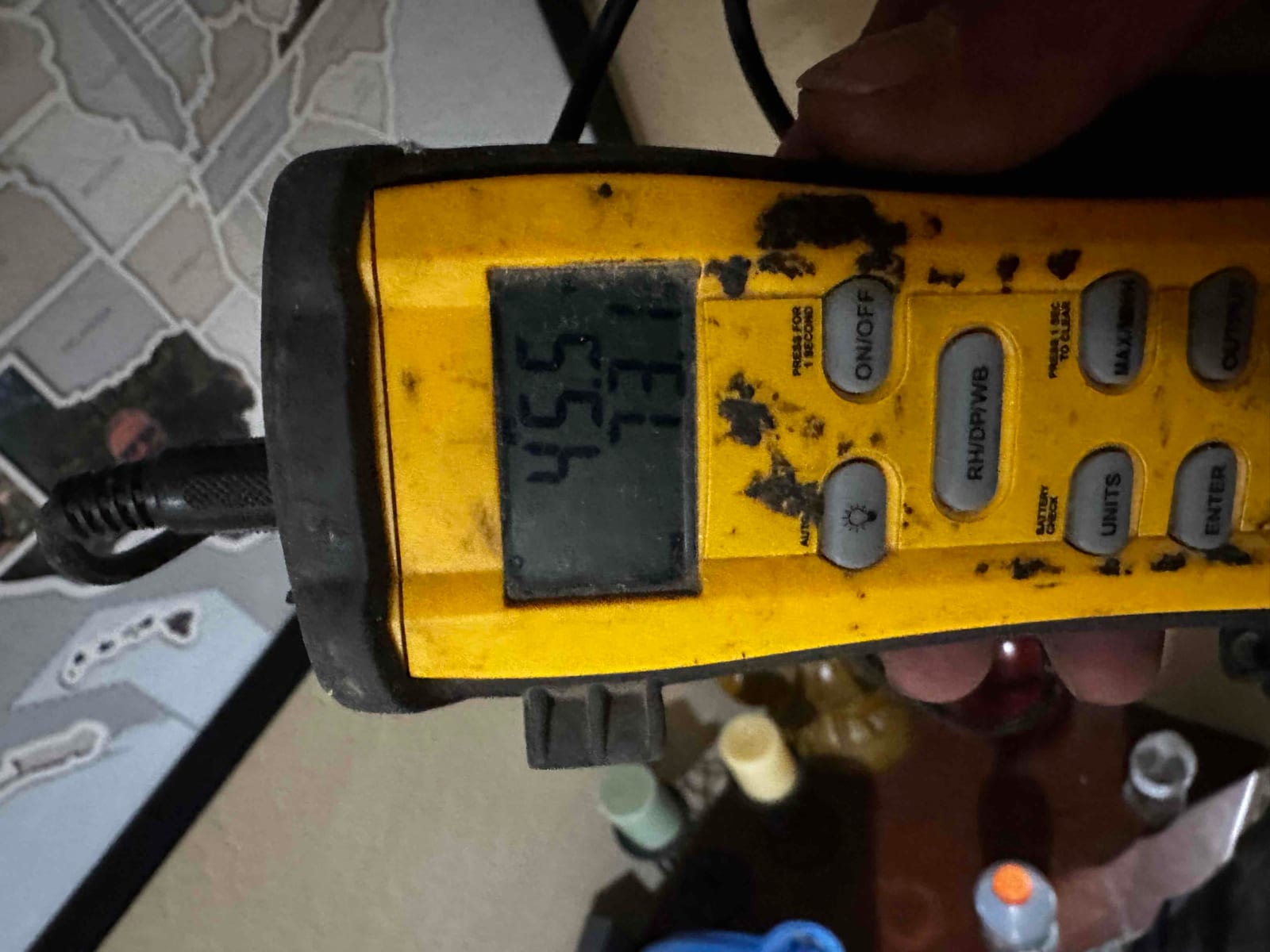 Digital thermometer displays 55.5 degrees Fahrenheit during supply air temperature check at the commercial package unit installation.