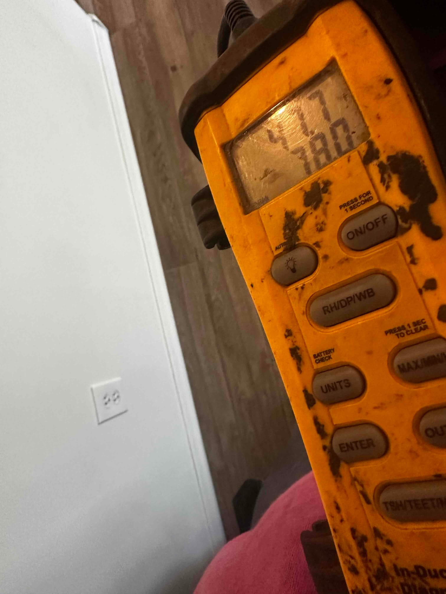 Digital thermometer handheld meter shows an air temperature reading during commissioning inside the conditioned space.