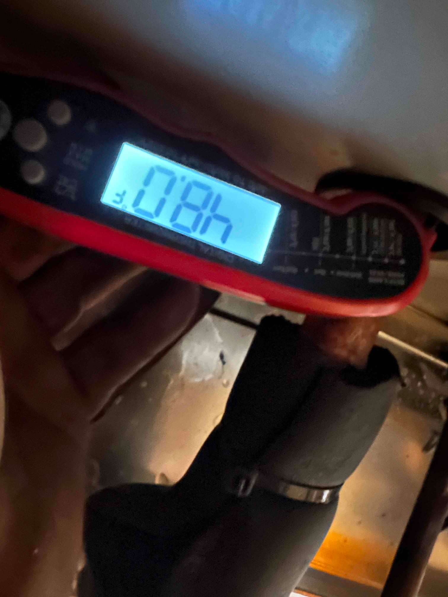 Digital thermometer on an insulated copper line shows 78°F during return air temperature check at the air handler.