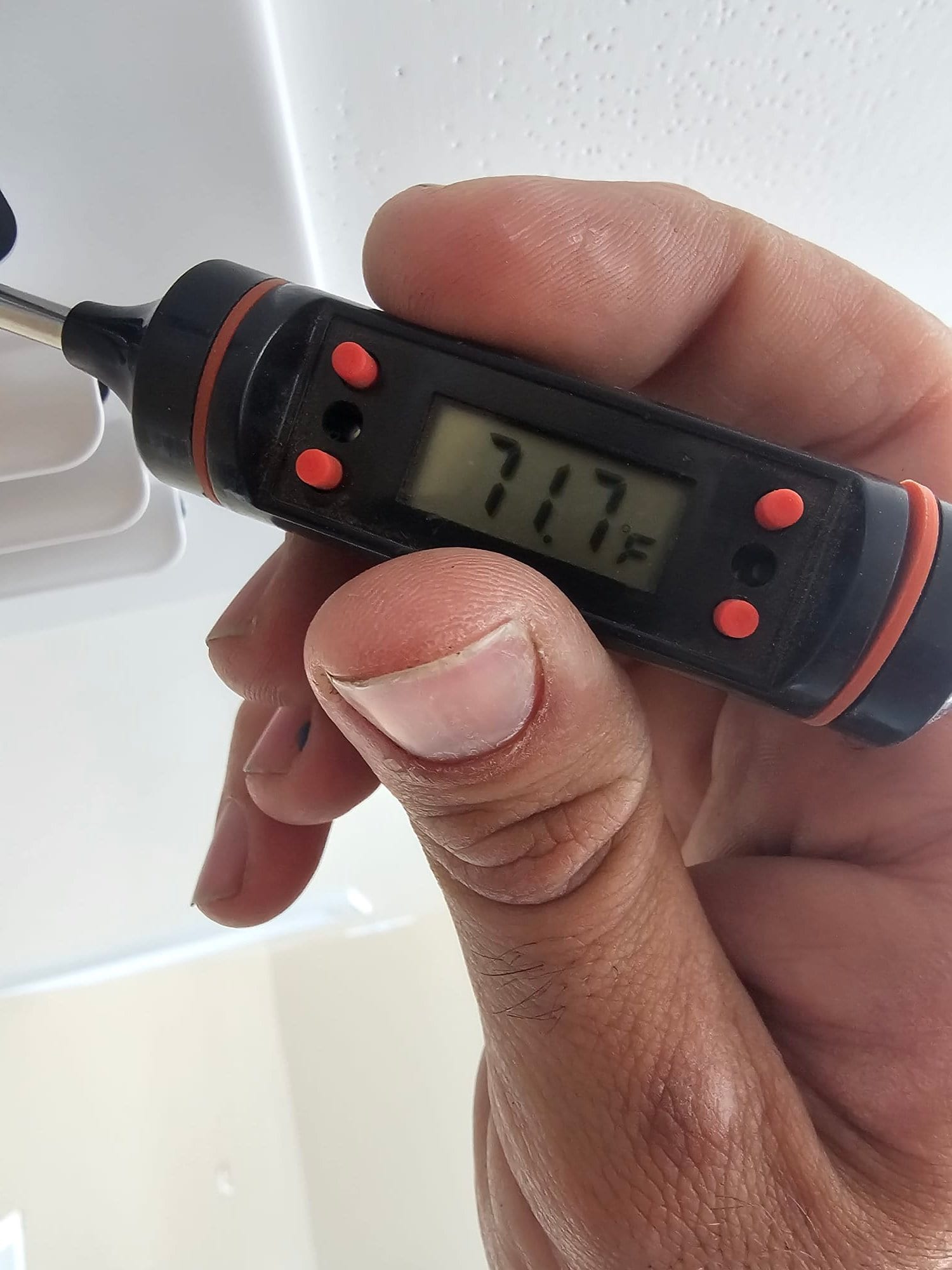Digital thermometer probe at a ceiling register displays 71.7°F, documenting return air temperature during commissioning.
