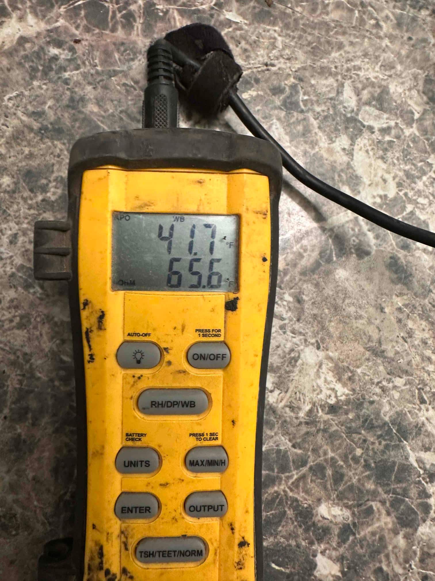 Digital thermometer probe displays 41.7°F and 65.6°F during air temperature checks on the newly installed system.