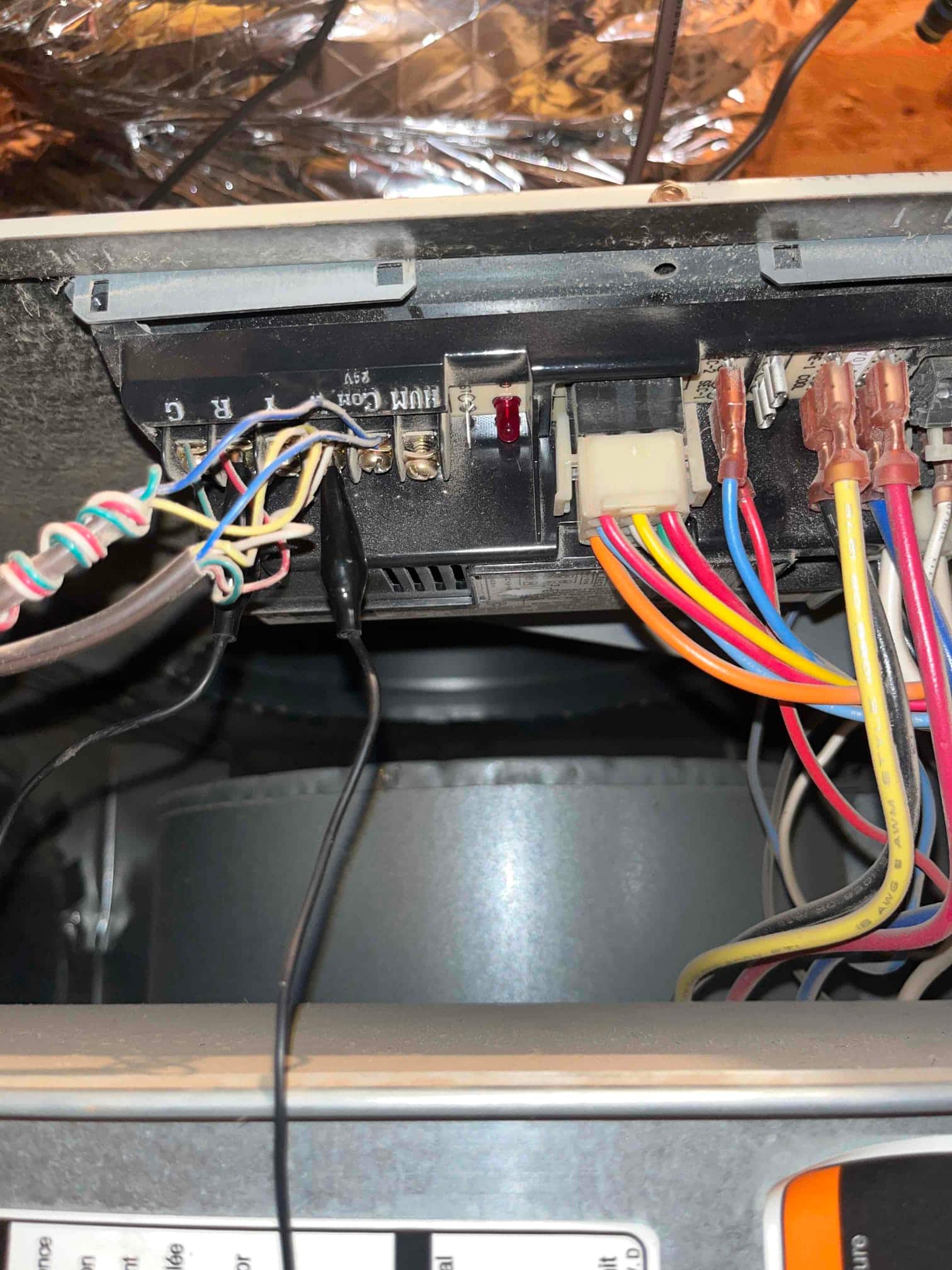 Furnace control board with connected low-voltage and high-voltage wiring above the inducer housing during draft motor replacement.