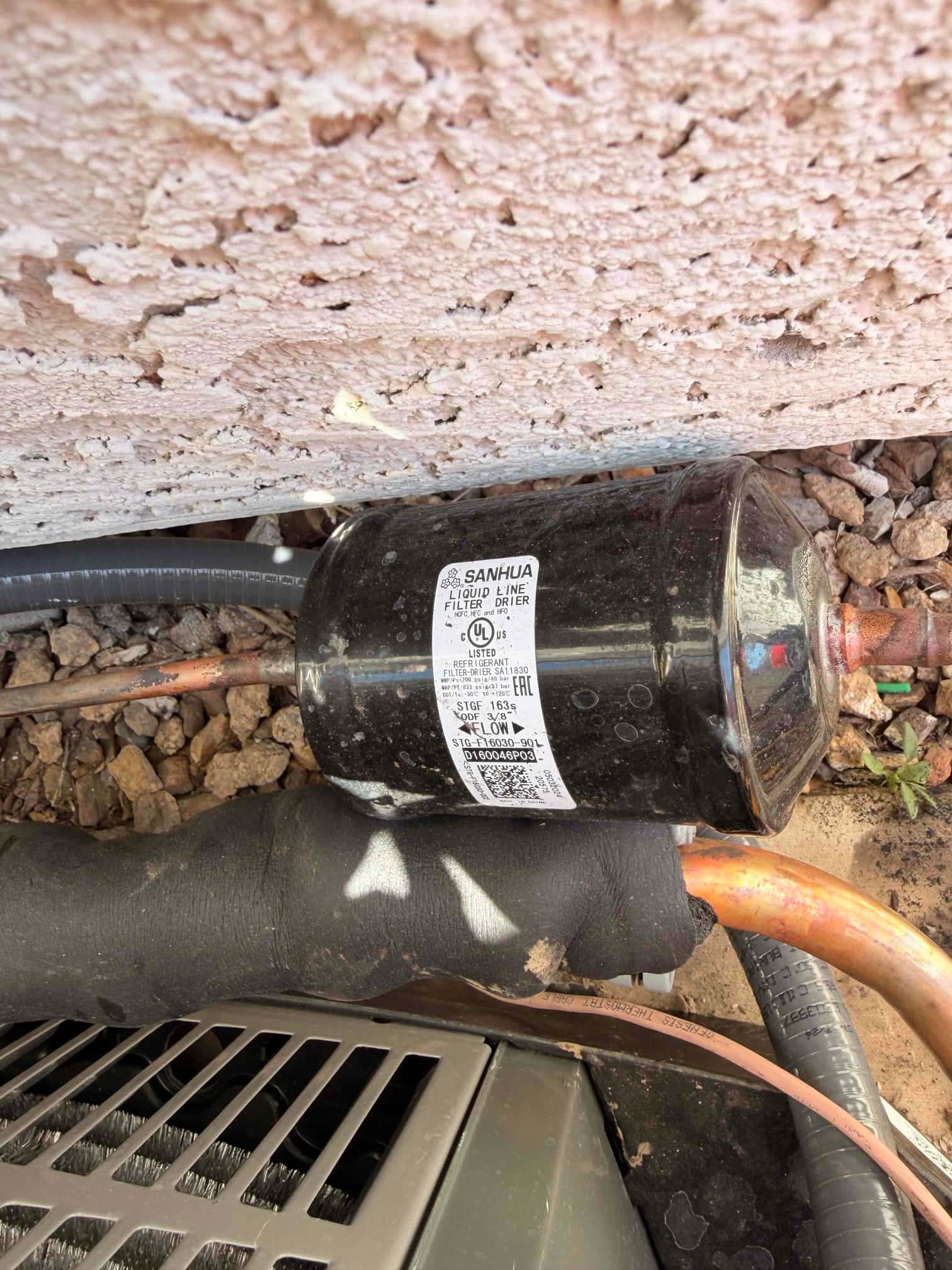 Insulated refrigerant lines with an inline liquid line filter drier installed next to the outdoor condenser cabinet.