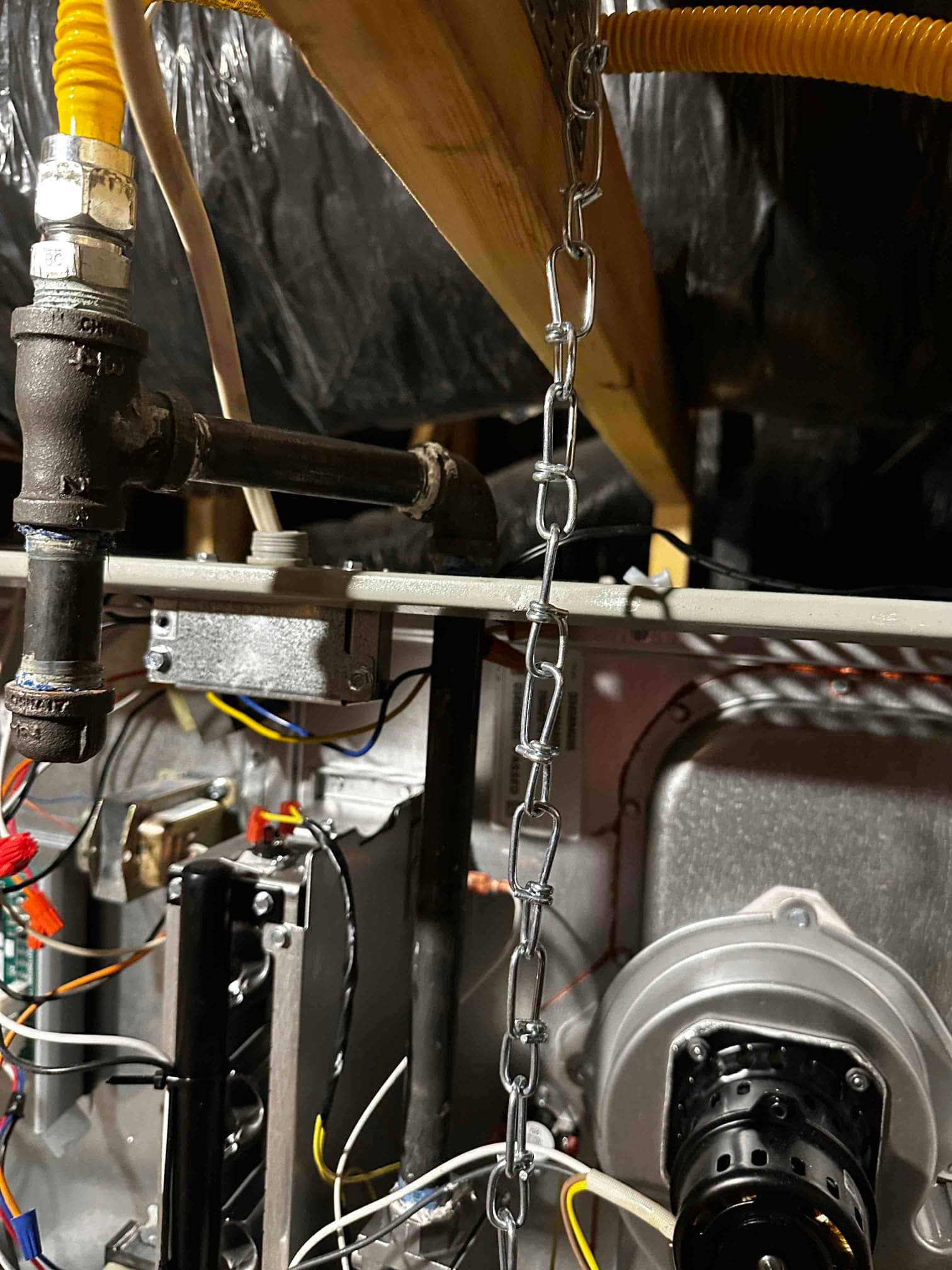 Interior furnace compartment showing new gas piping with drip leg, flexible connector, wiring, and induced draft motor assembly.