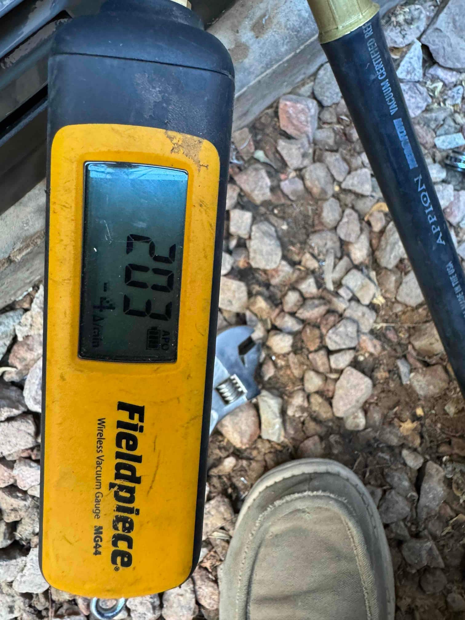 Micron gauge connected during evacuation shows 203 microns, confirming a deep vacuum prior to refrigerant charging.