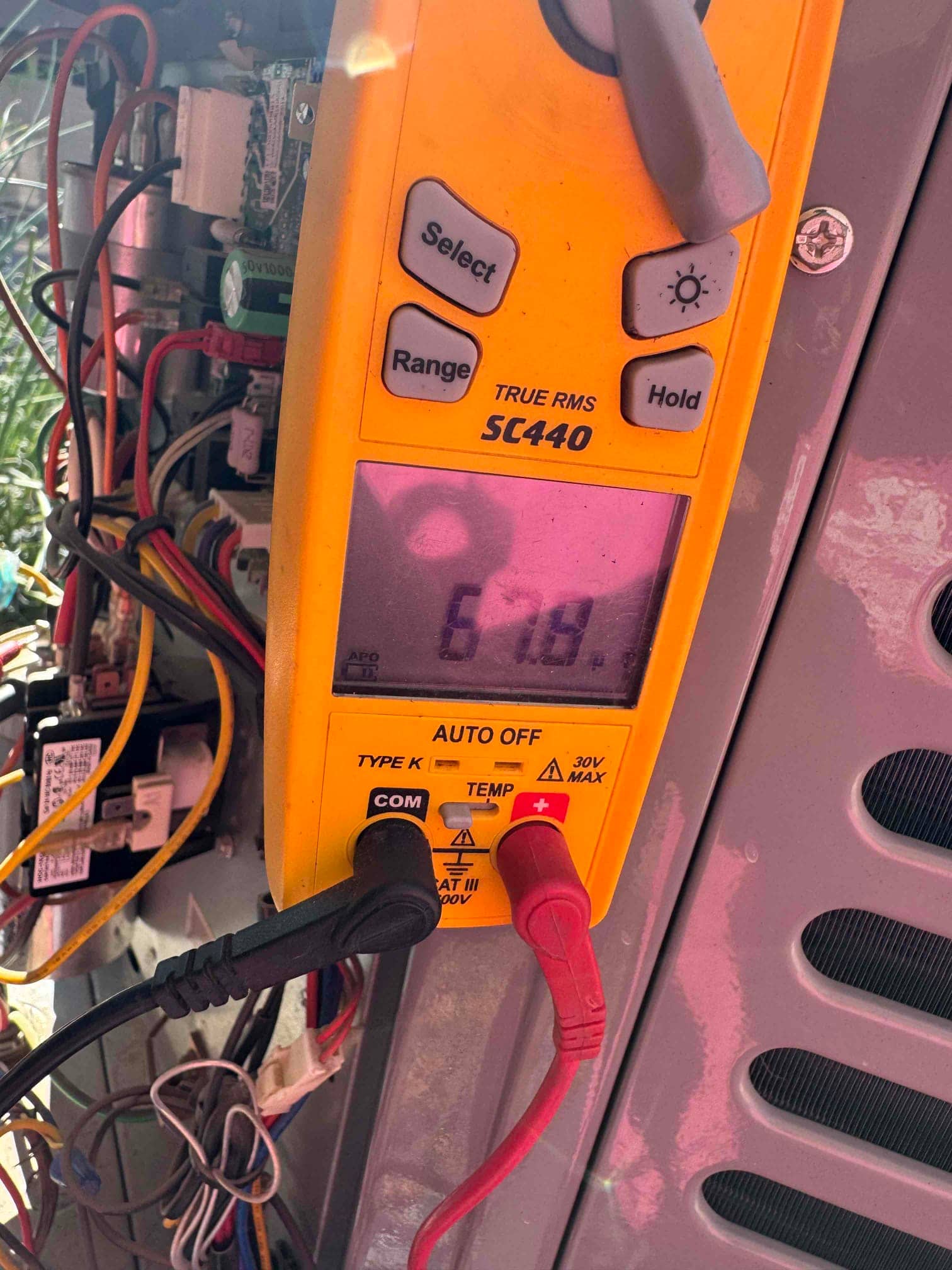 Multimeter shows 6.19 V while probing the condenser’s control circuit terminals with red and black leads connected.