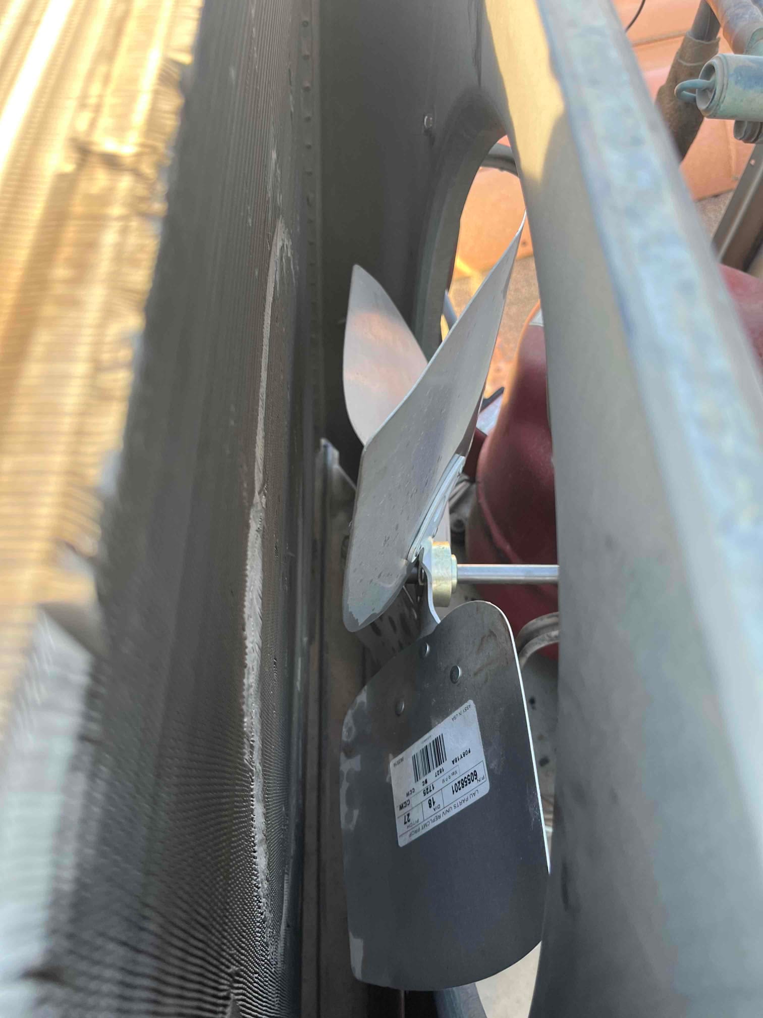 New condenser fan blade assembly installed next to the outdoor coil, showing clean blades and mounting hardware inside the unit.