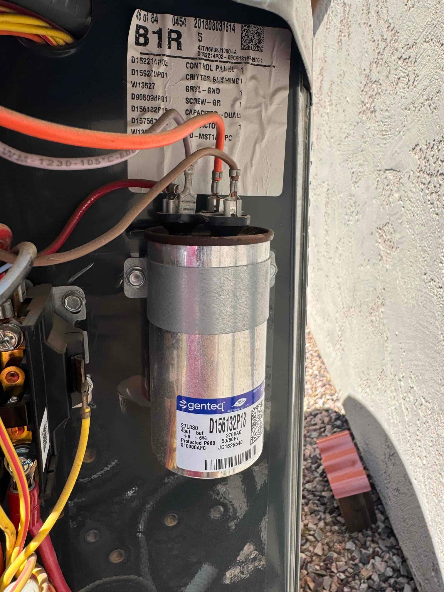 New dual-run capacitor installed in the condenser compartment with connected terminals and neatly routed control wiring visible nearby.