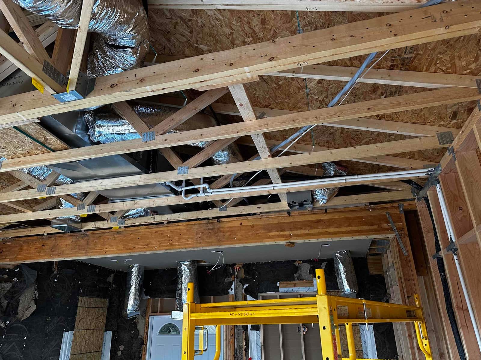 New flexible ductwork and metal plenum installed in open ceiling framing, with condensate drain and multiple supply runs routed.