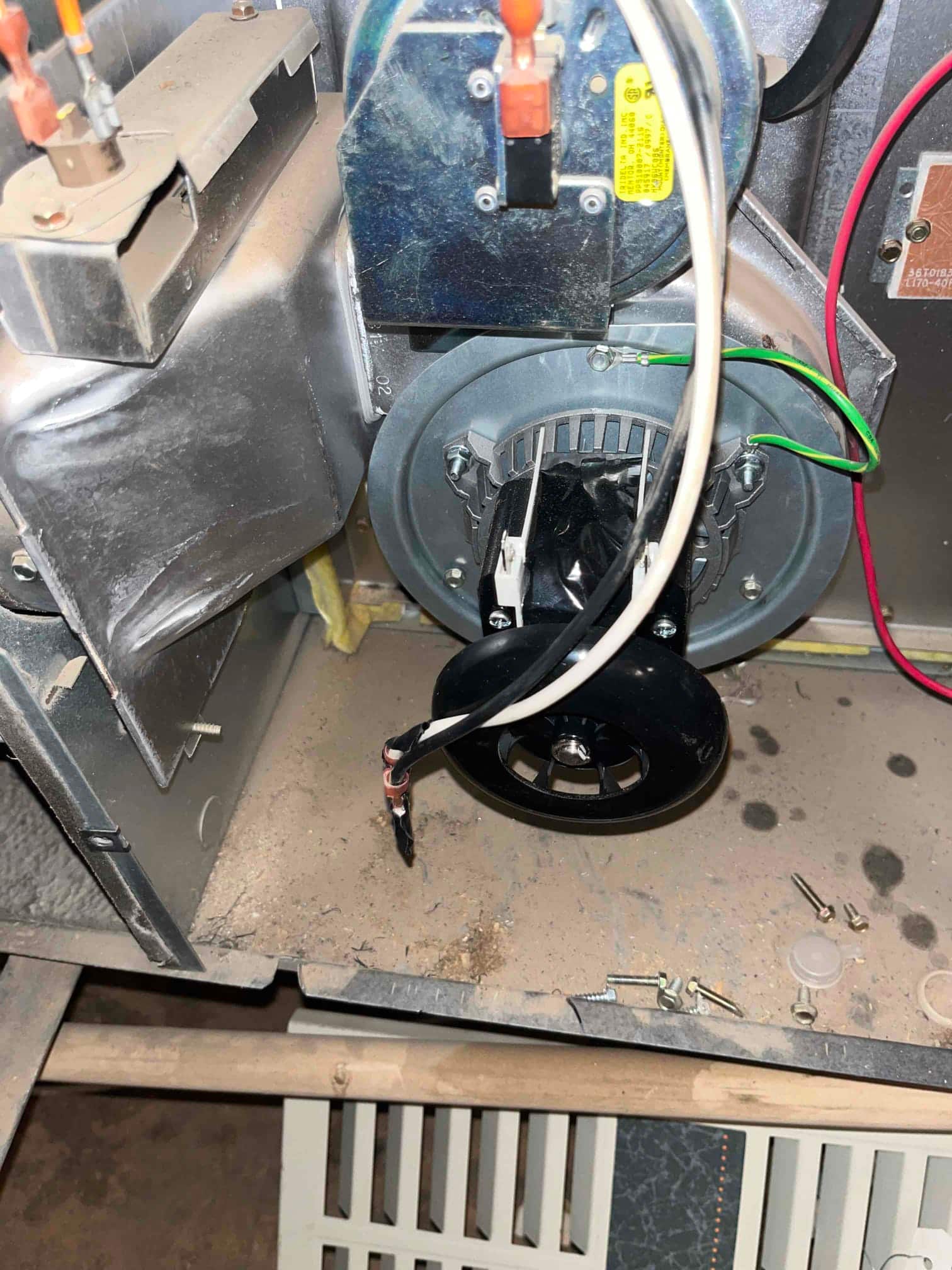 New inducer draft motor assembly installed inside a furnace cabinet, showing wiring connections and mounting hardware on the housing.