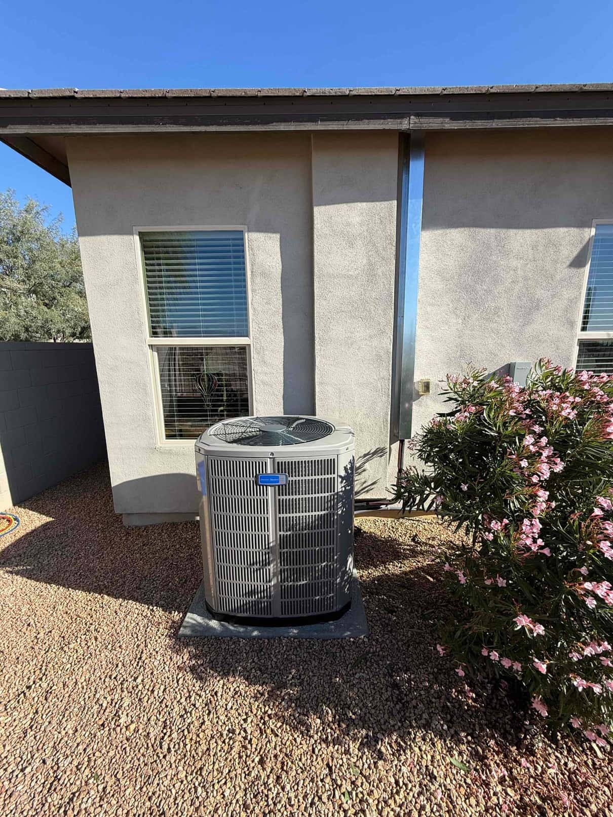 New outdoor condenser set on a level pad with insulated line set and sealed wall penetration beside the home.