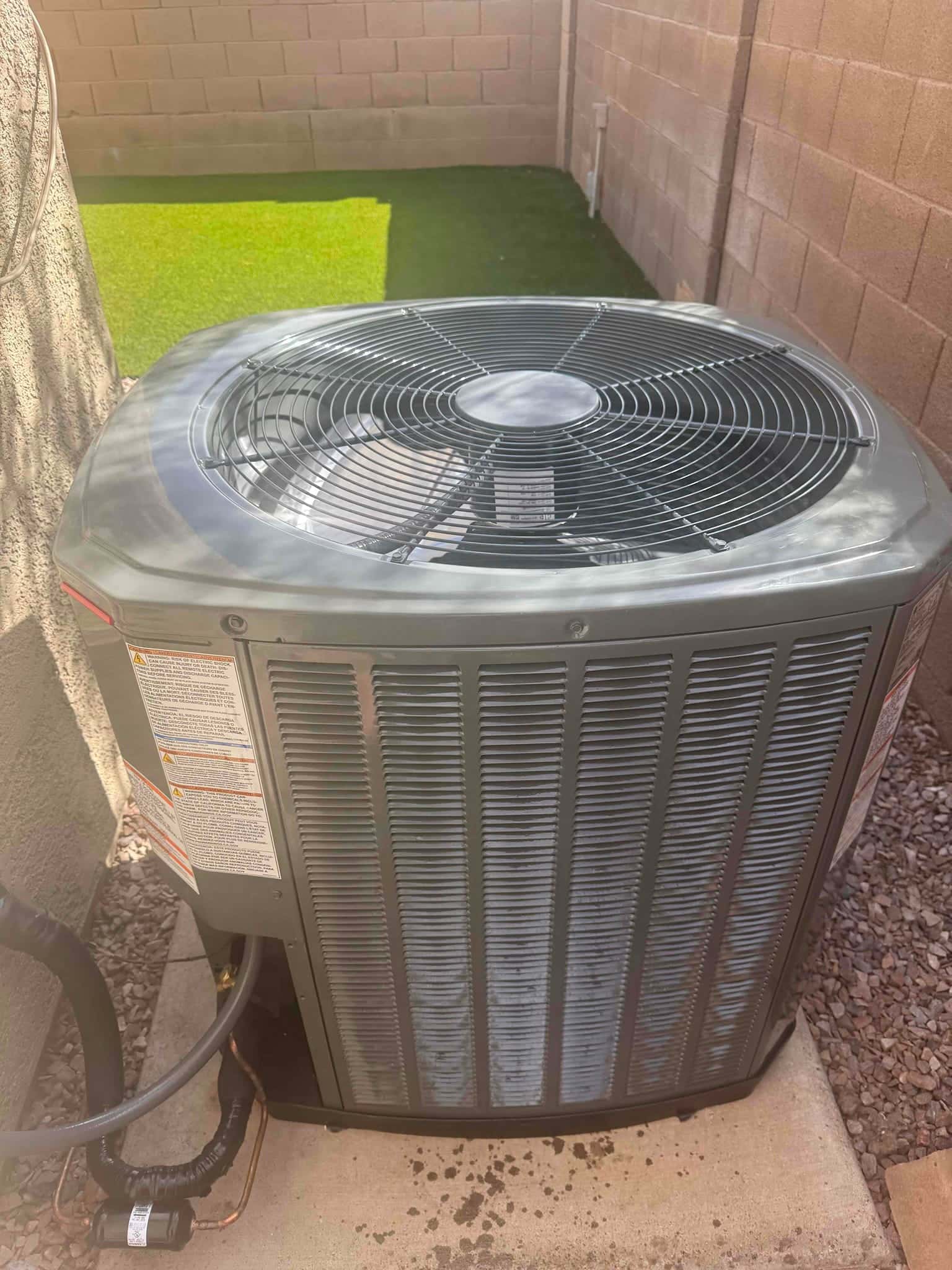 New outdoor condenser set on a level pad with insulated refrigerant lines routed and sealed at the wall penetration.