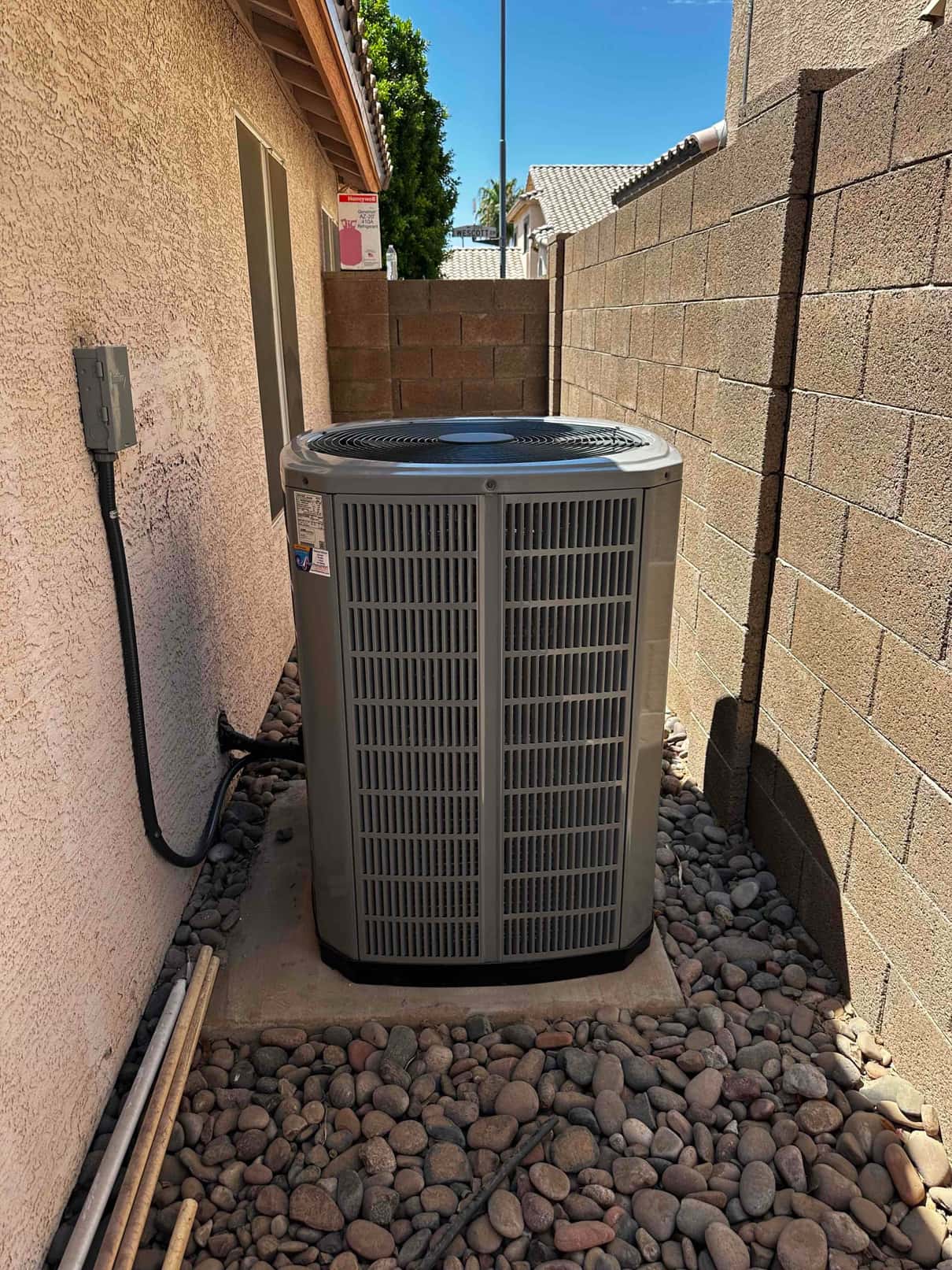 New outdoor heat pump condenser set on a level pad with insulated line set and exterior disconnect installed.