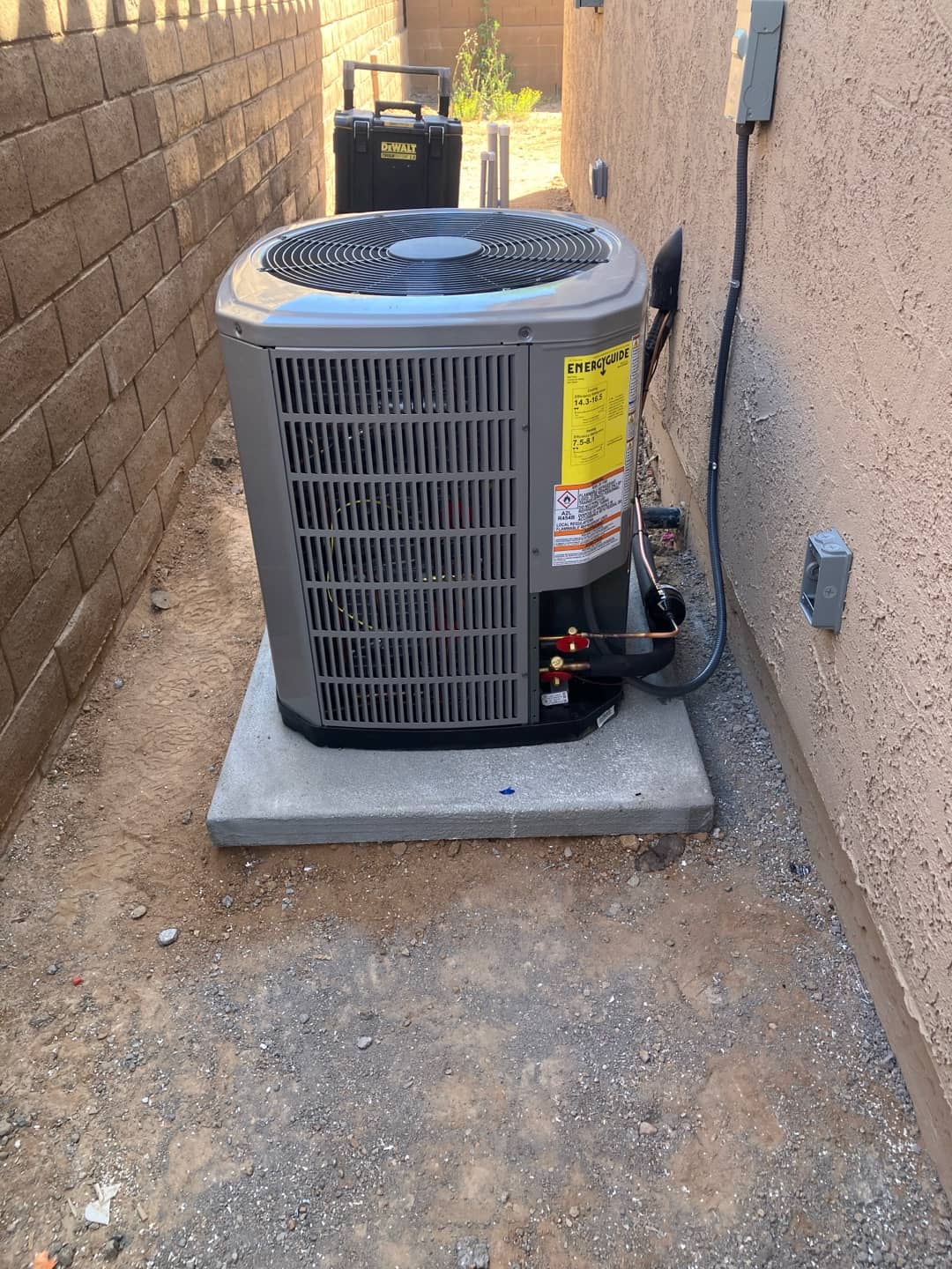 New outdoor heat pump condenser set on a level pad with insulated line set and exterior disconnects installed.