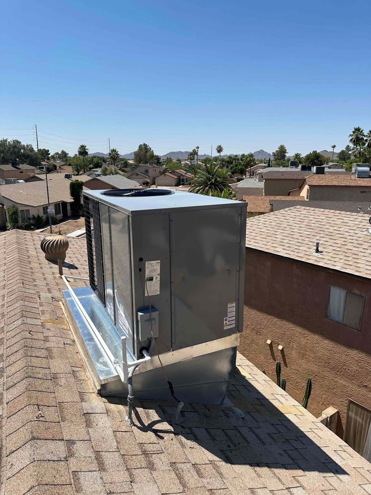 New packaged rooftop heat pump installed on curb with sealed duct transitions, insulated condensate drain, and electrical disconnect mounted.