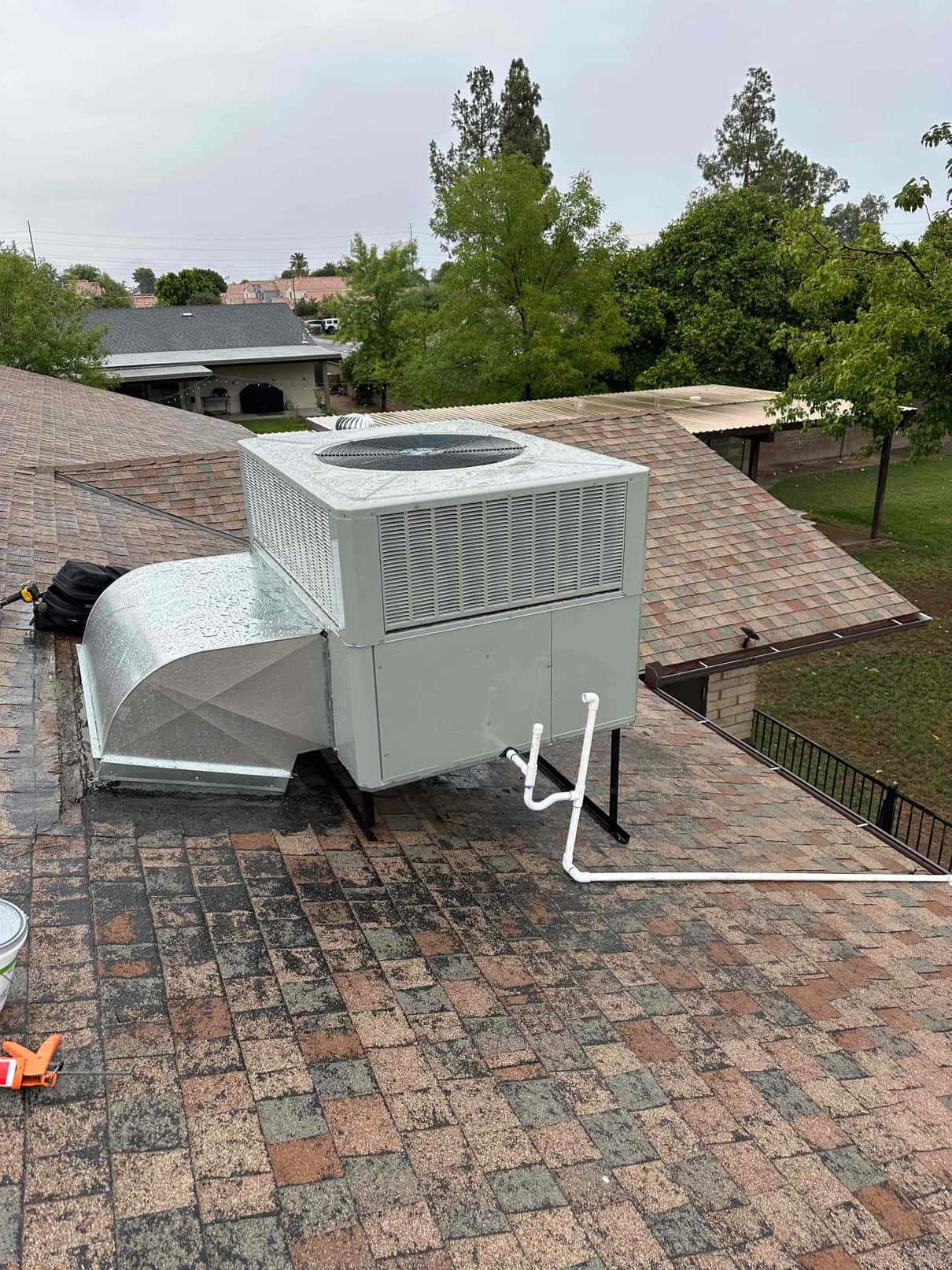 New rooftop commercial package unit set on curb with sealed duct transition and newly routed condensate drain piping.