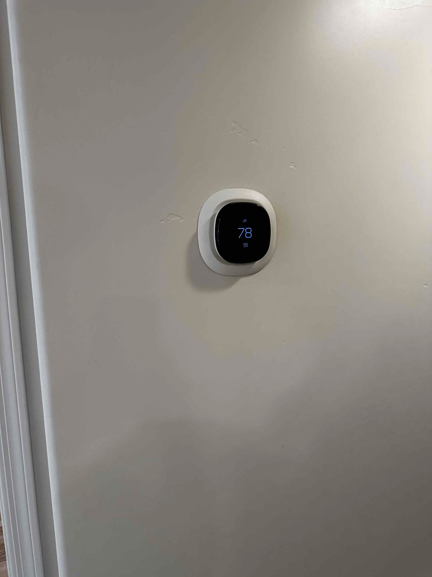 New wall-mounted smart thermostat installed and powered on, displaying a room temperature reading of 78 degrees.