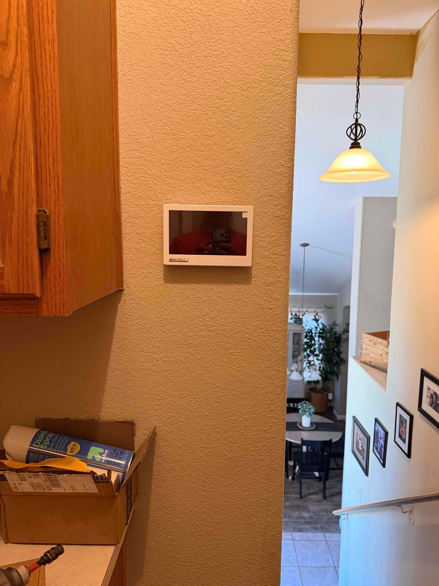 New wall-mounted thermostat installed near the stairway, with finished wiring concealed for a clean appearance.