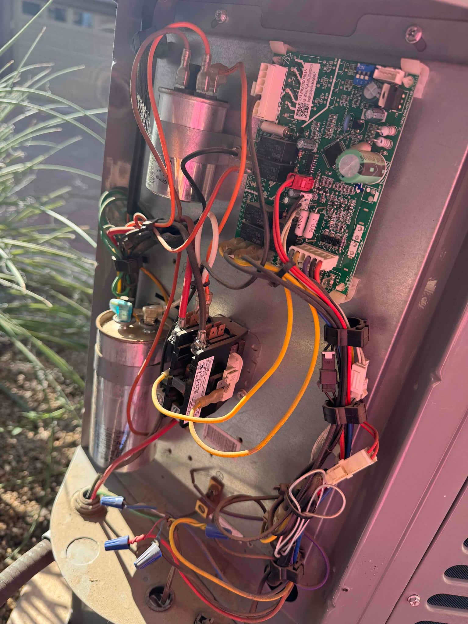 Open condenser control compartment showing control board, contactor, dual run capacitor, wiring connectors, and service disconnect wiring.