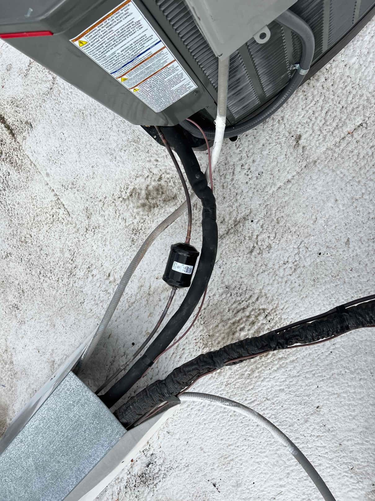 Outdoor condenser connections with insulated refrigerant lines, electrical whip, and drain line routed along the rooftop surface.
