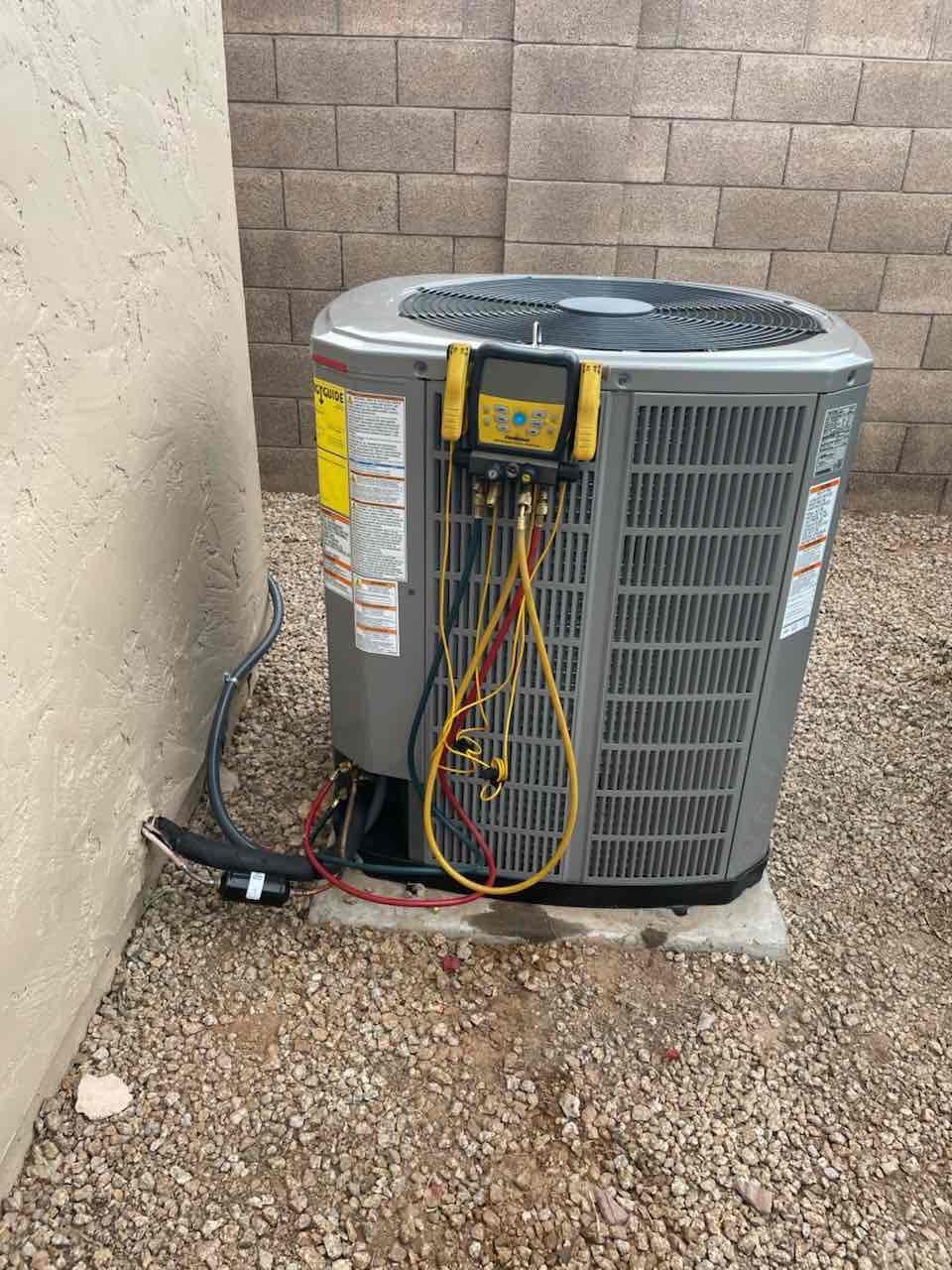 Outdoor condenser set on a level pad with digital manifold connected to service ports and insulated line set routed to the wall.