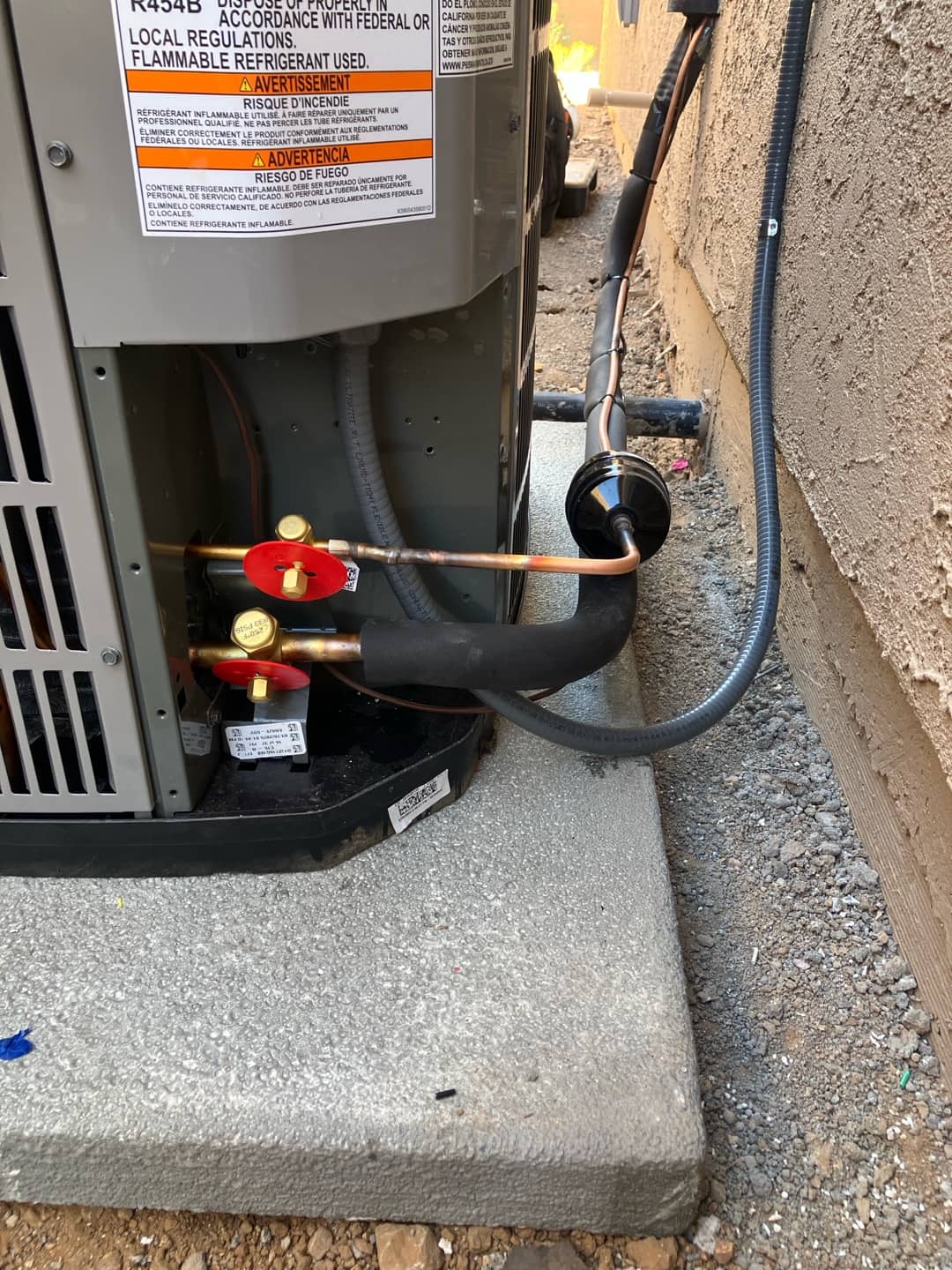 Outdoor heat pump connections show insulated suction line, liquid line with filter-drier, and service valves on a new condenser pad.