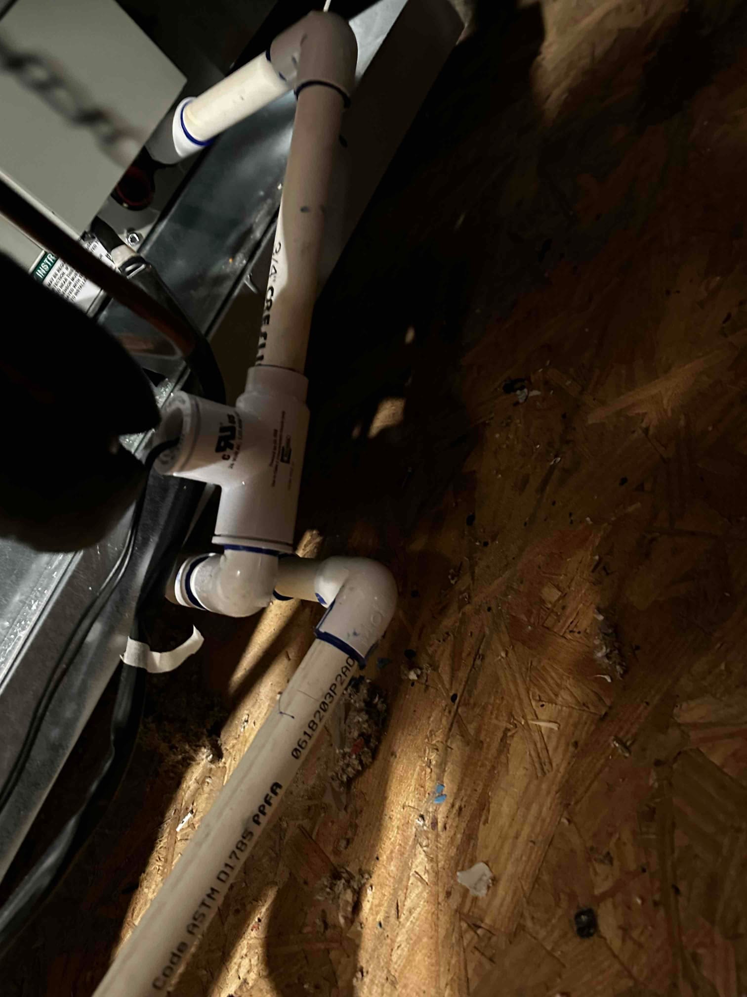 PVC condensate drain assembly with cleanout and trap connected to the air handler, sealed joints and proper fittings visible.