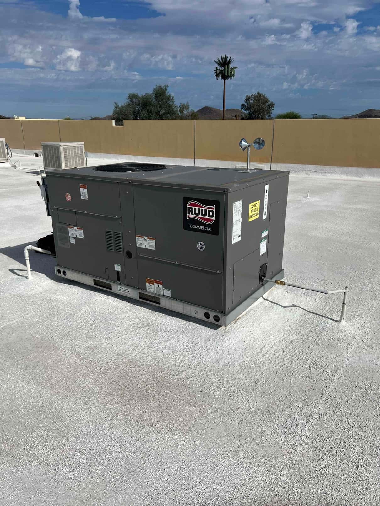 Rooftop packaged HVAC unit newly set on a coated roof with connected condensate drain and sealed penetrations.