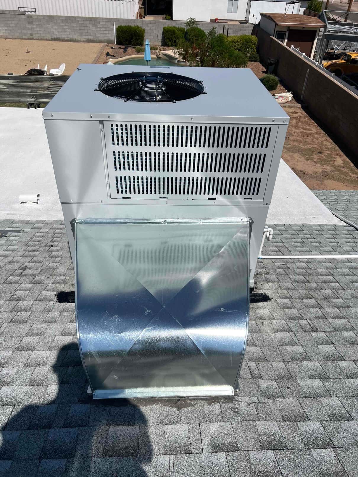 Rooftop packaged unit installed with new galvanized curb transition and sealed roof penetration, viewed from above the supply/return duct connection.