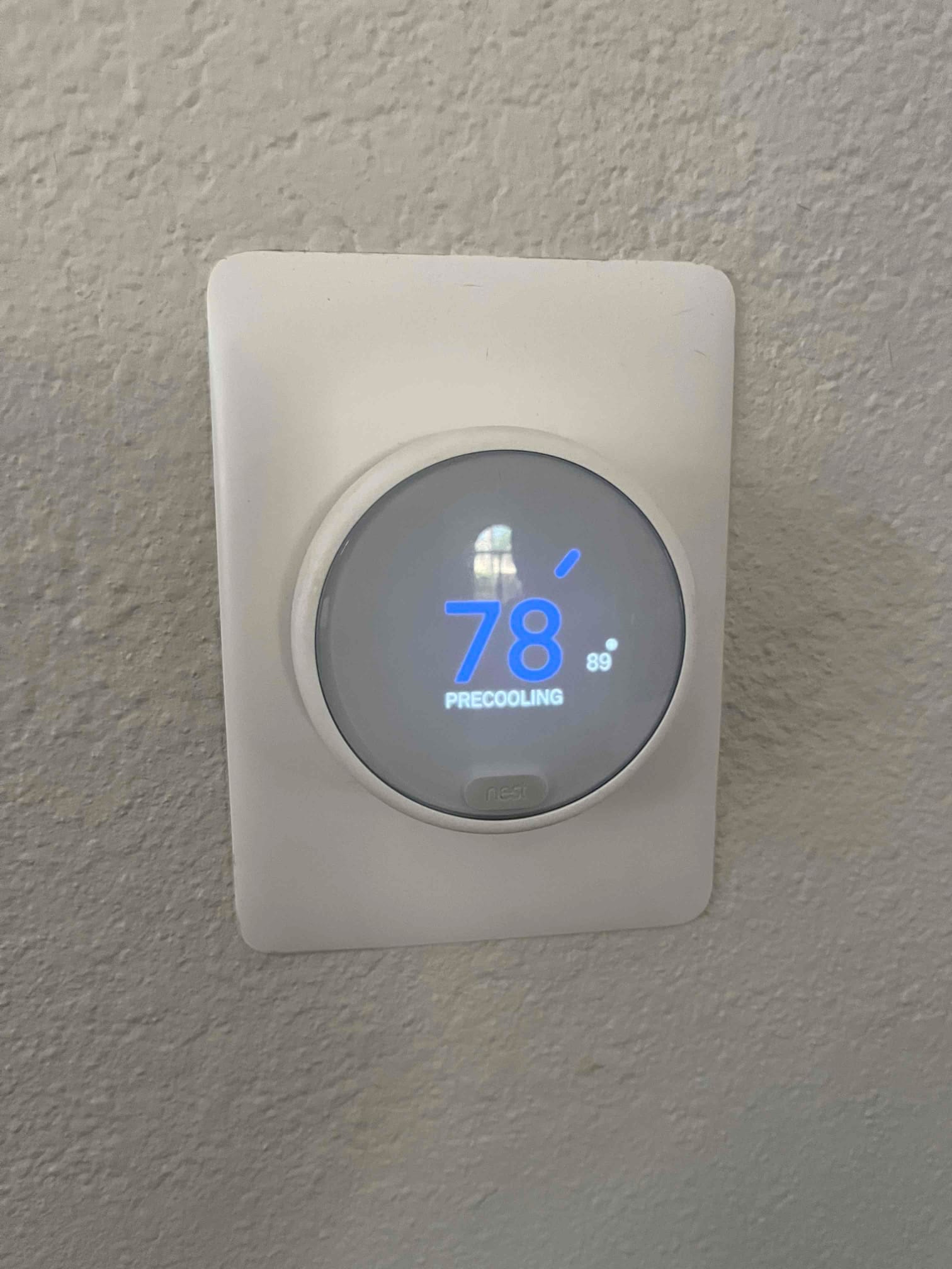 Smart thermostat display shows 78 °F setpoint with system status indicating precooling mode on the wall.