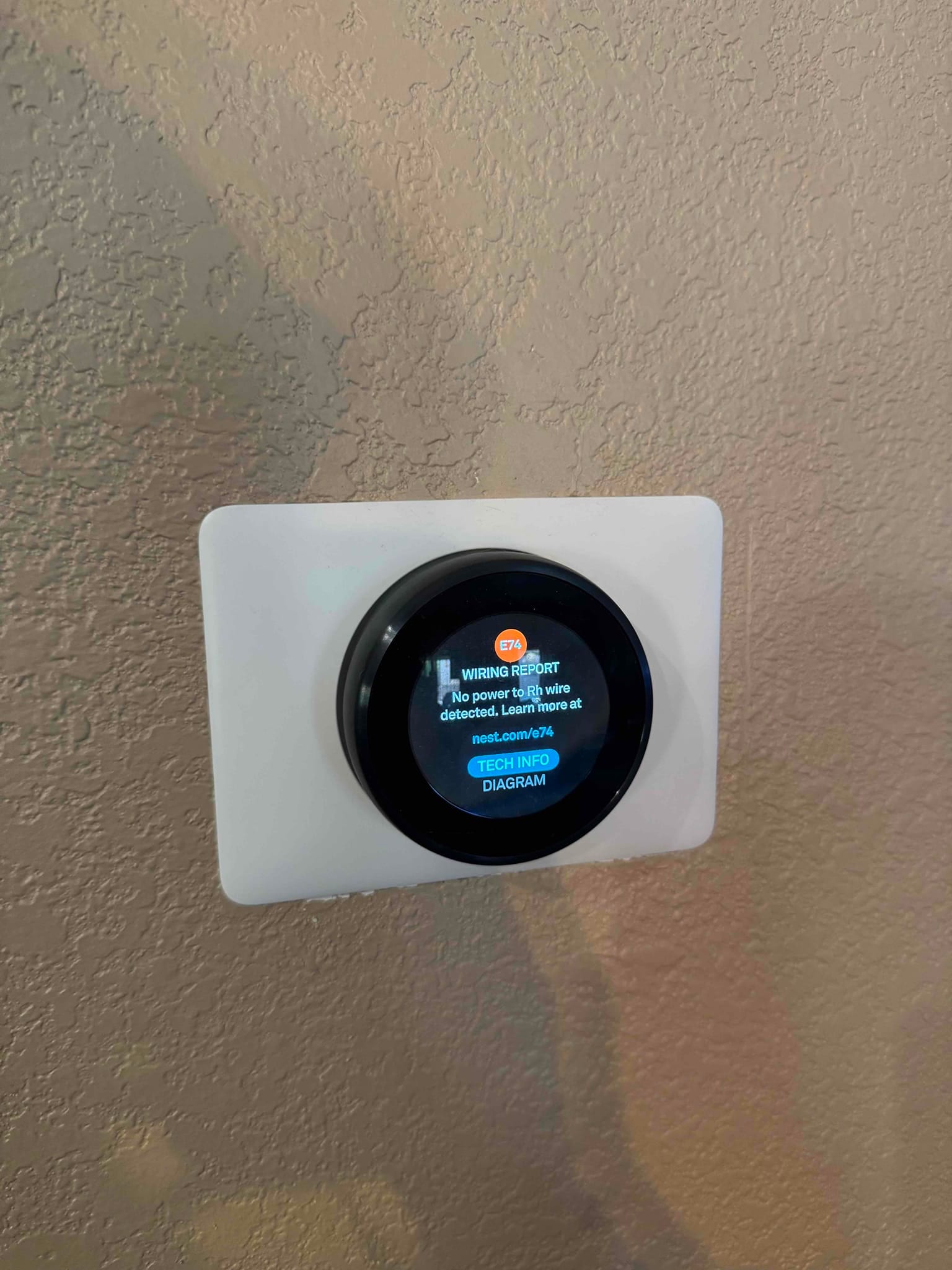 Smart thermostat on interior wall displays a wiring report screen with menu options and a circular control interface.