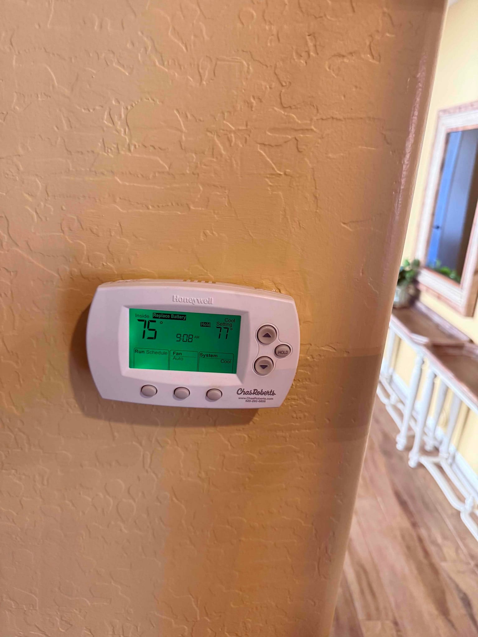 Wall-mounted digital thermostat powered on, displaying indoor temperature and cooling setpoint after system installation.