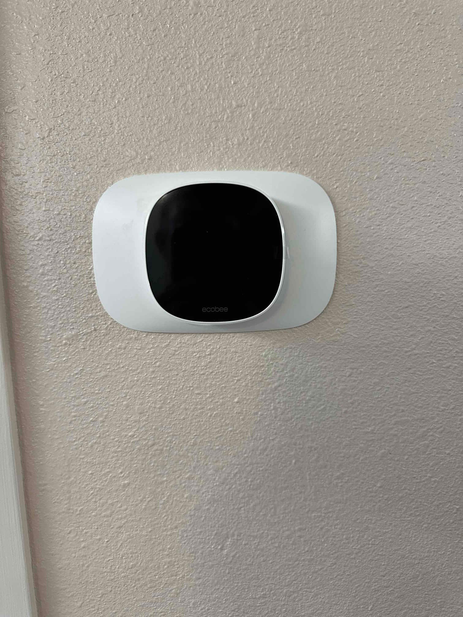 Wall-mounted smart thermostat installed on a trim plate, showing a clean finished appearance for the control location.