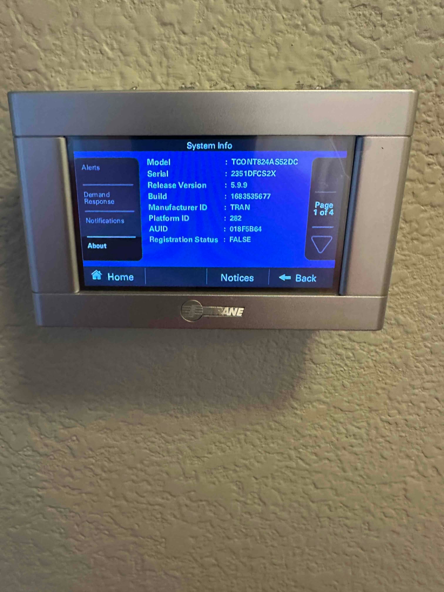 Wall-mounted thermostat displays system information menu after installation, showing model, serial, software version, and registration status.
