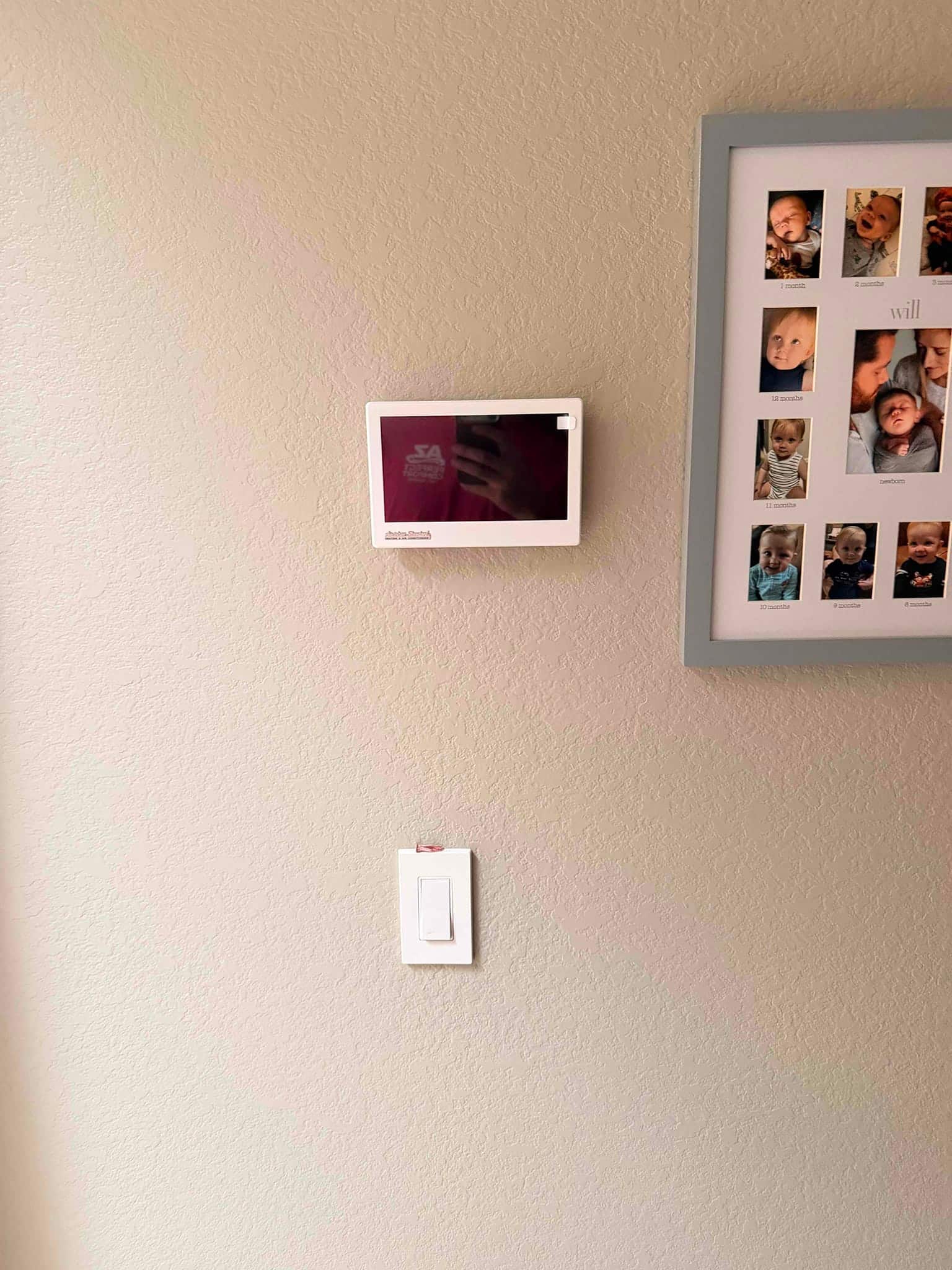 Wall-mounted thermostat installed and leveled near a light switch inside the home, ready for system commissioning.