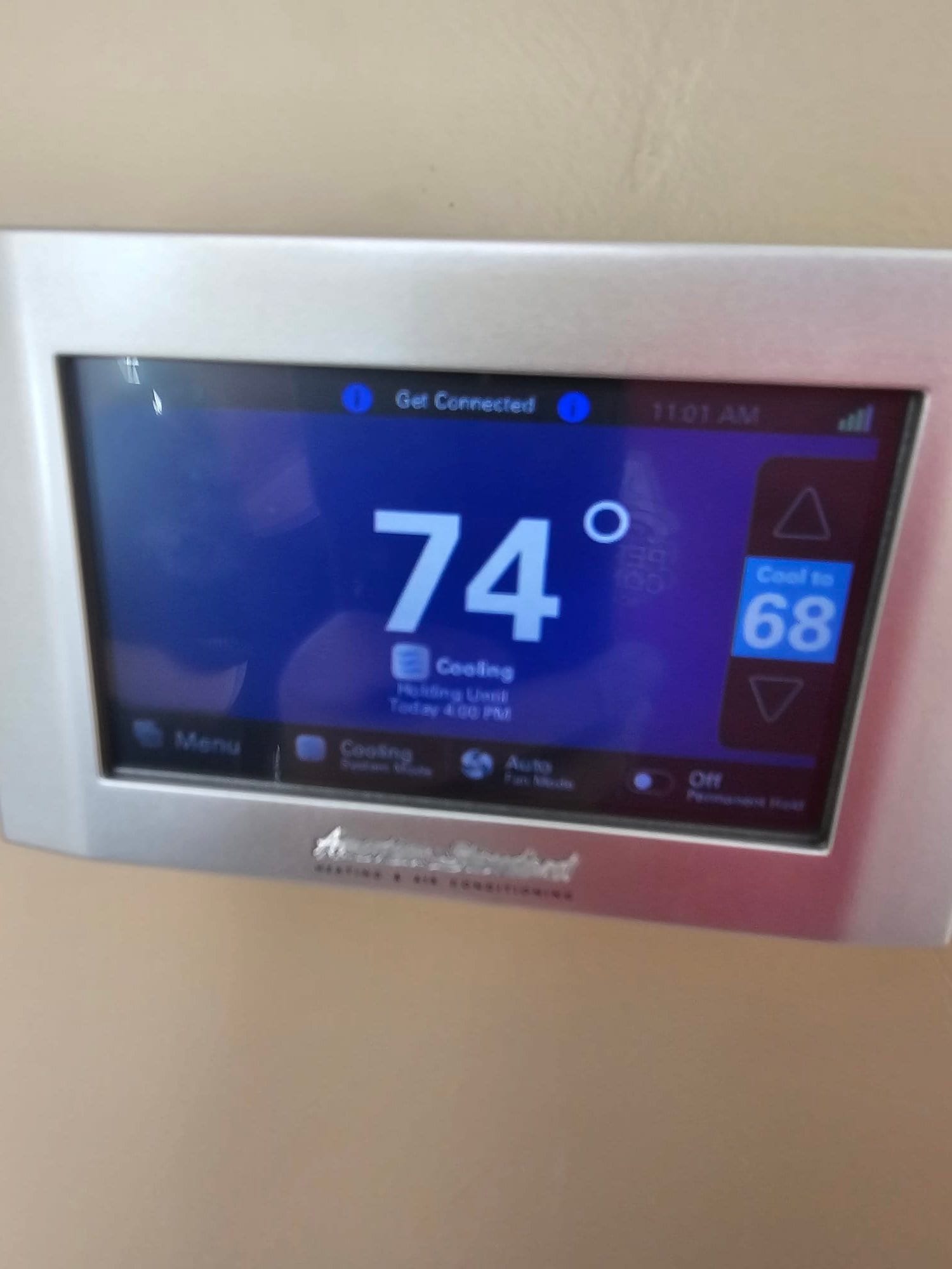 Wall-mounted touchscreen thermostat displays 74 degrees indoor temperature with cooling mode active and a setpoint of 68.