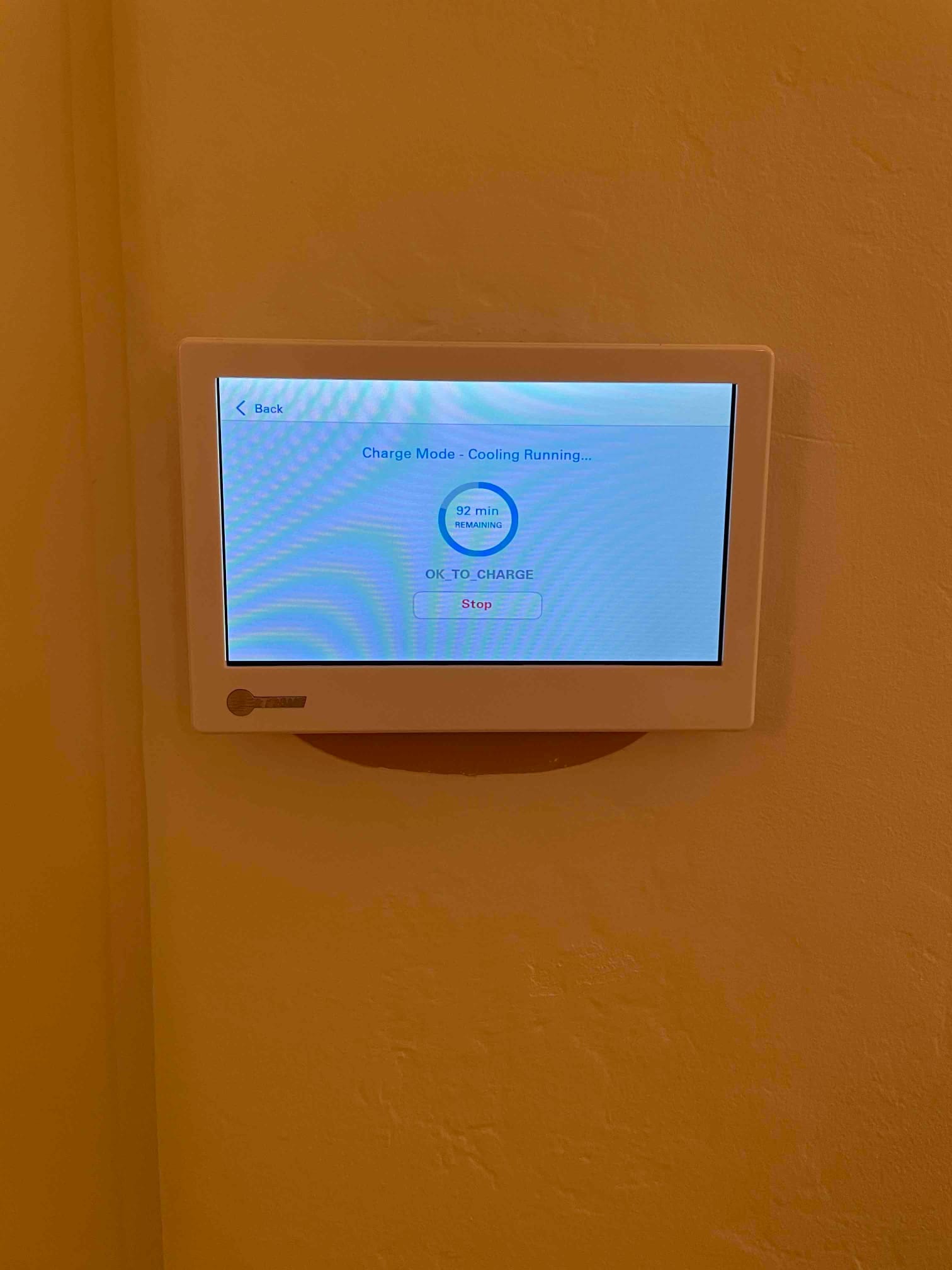 Wall-mounted touchscreen thermostat displays charge mode with cooling running and a countdown timer visible on the screen.
