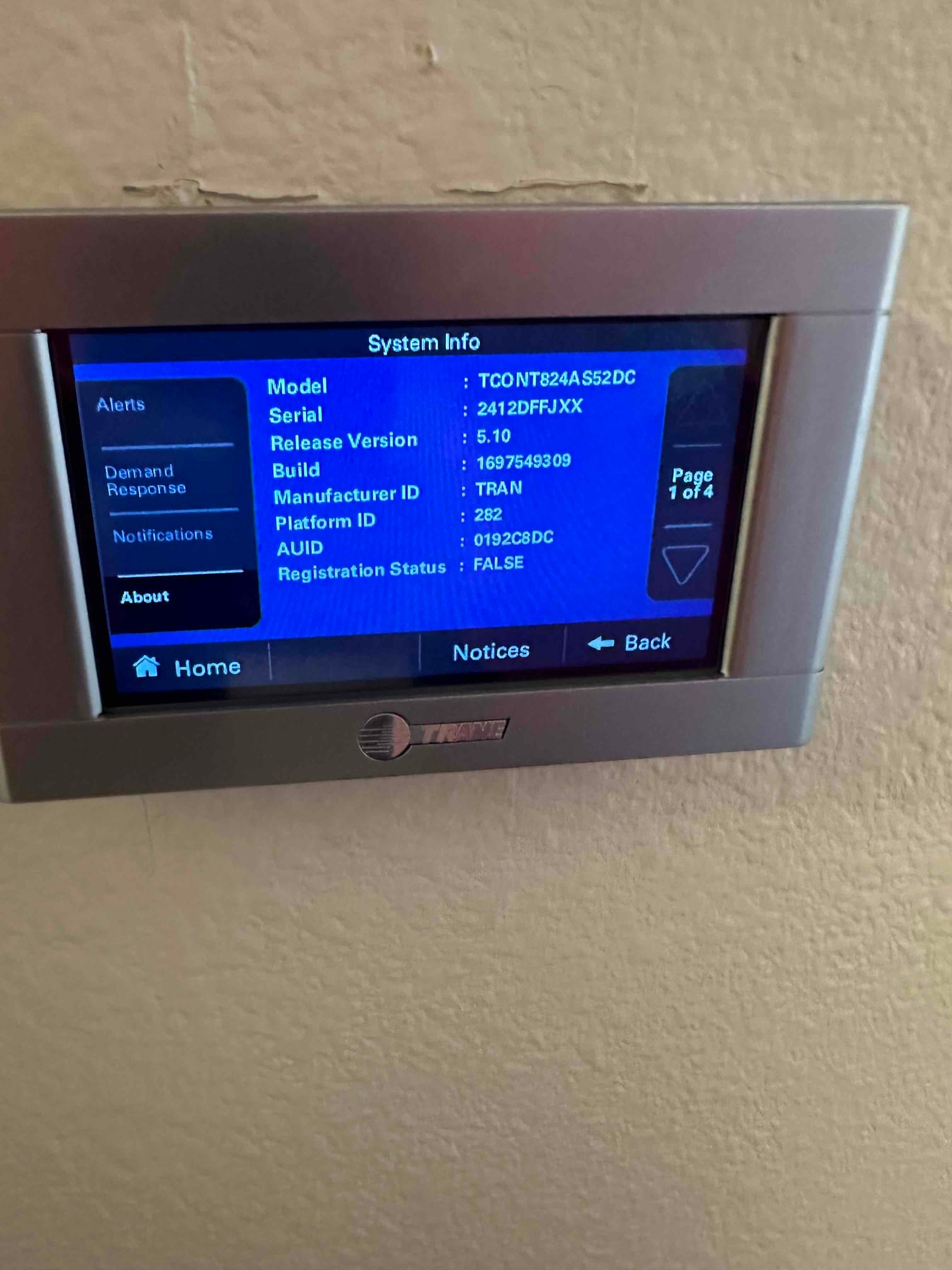 Wall-mounted touchscreen thermostat displays system information menu during setup after HVAC installation.