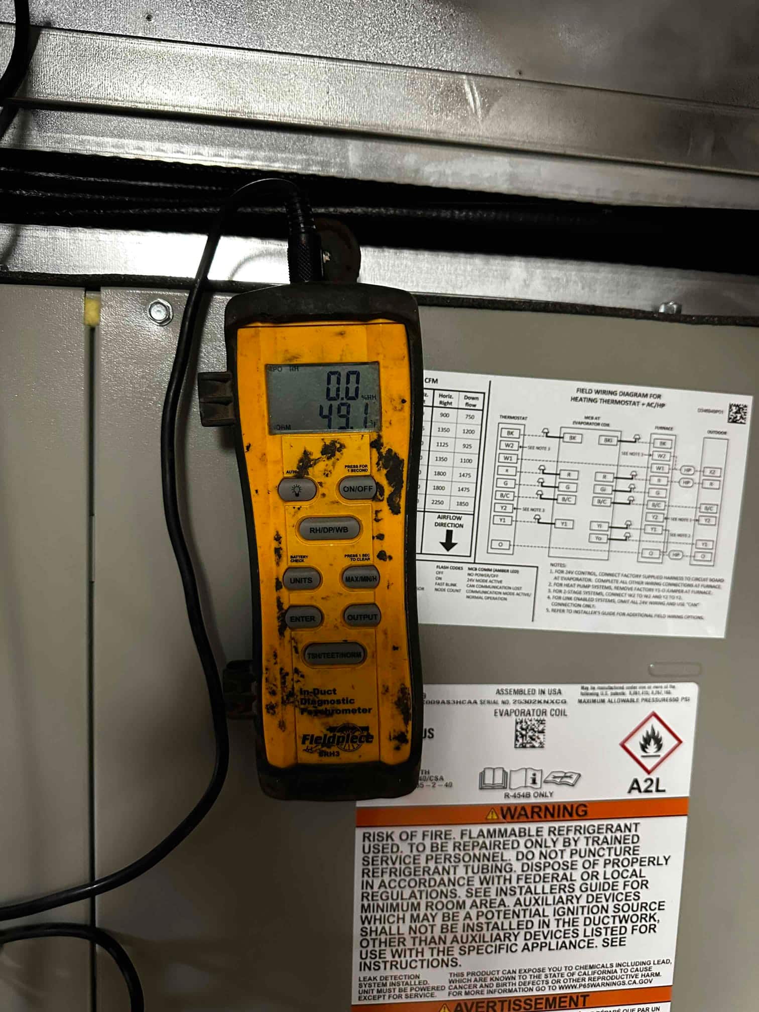 Digital in-duct diagnostic anemometer mounted at the air handler shows a 49.1 reading during airflow measurement.