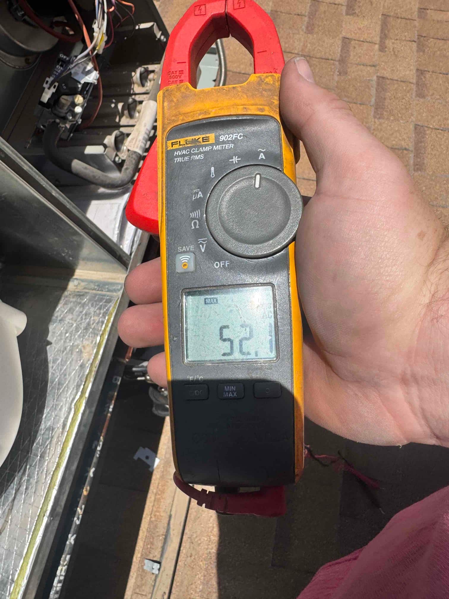 Clamp meter shows 52.1 A on a conductor at the outdoor condenser during testing.